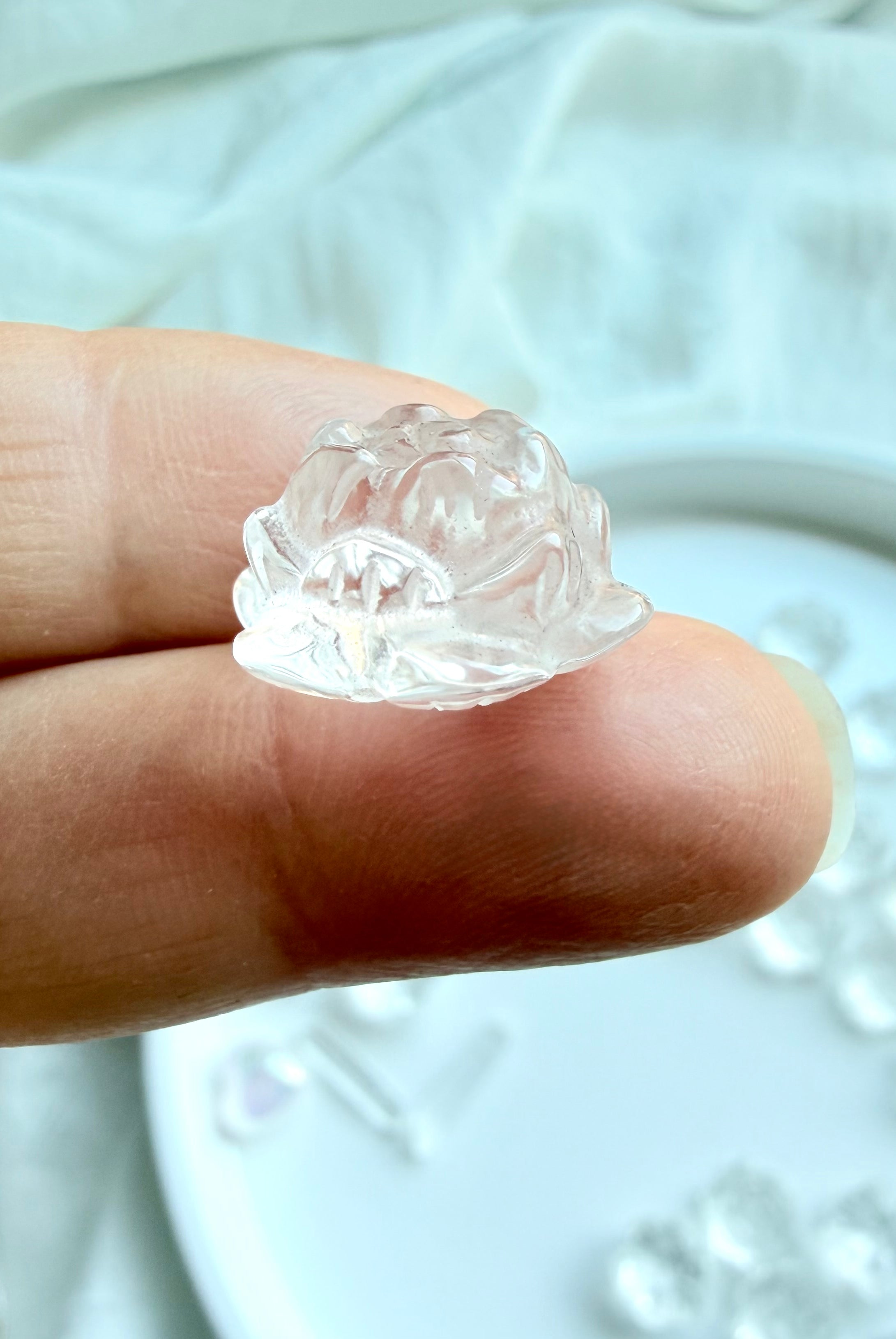 Tiny Clear Quartz lotus flower carving, side view shown on fingertip for scale, ideal as a pocket stone or crystal grid stone