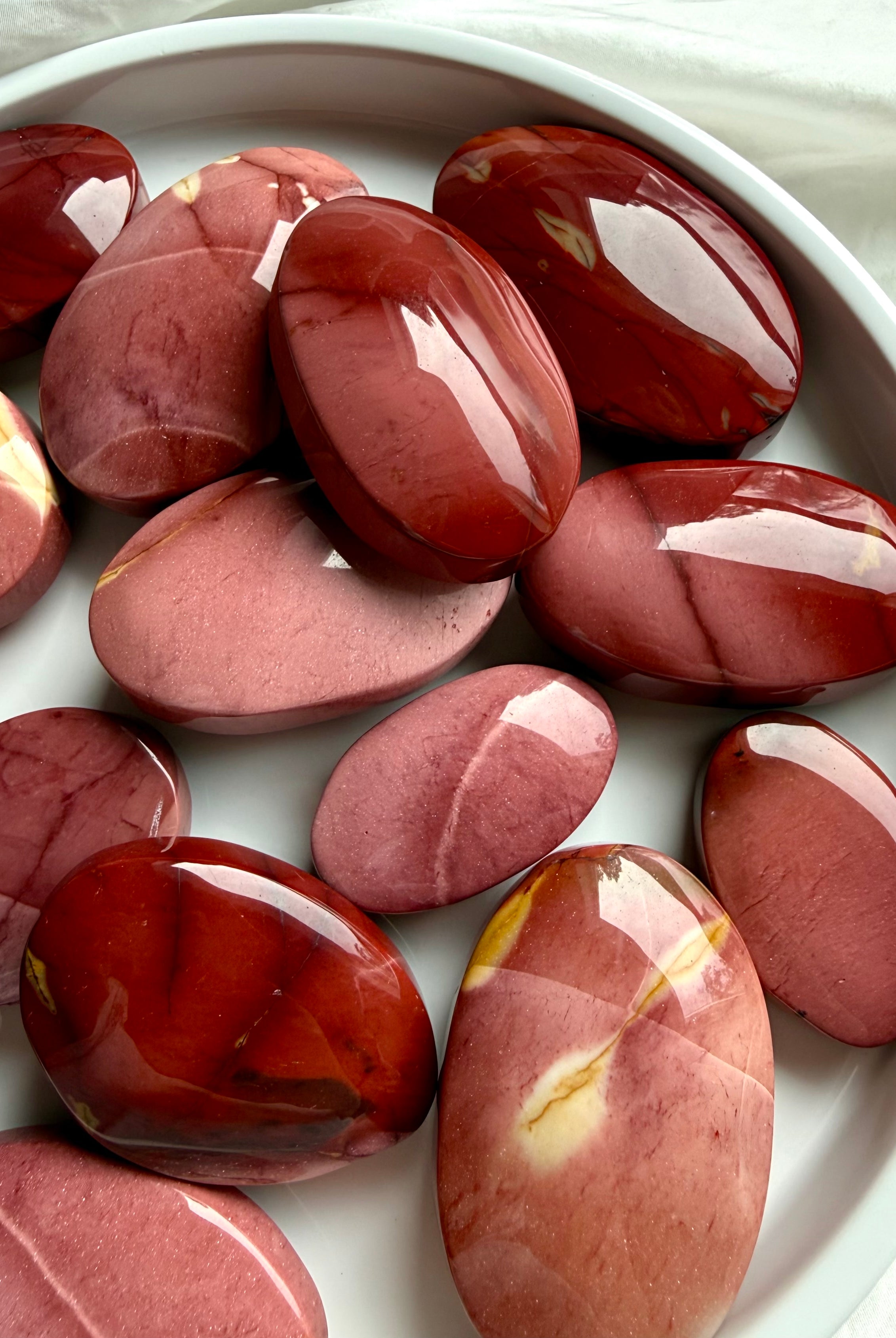 polished Mookaite Jasper palm stones in earthy red and mauve tones for grounding, strength, vitality, and emotional balance