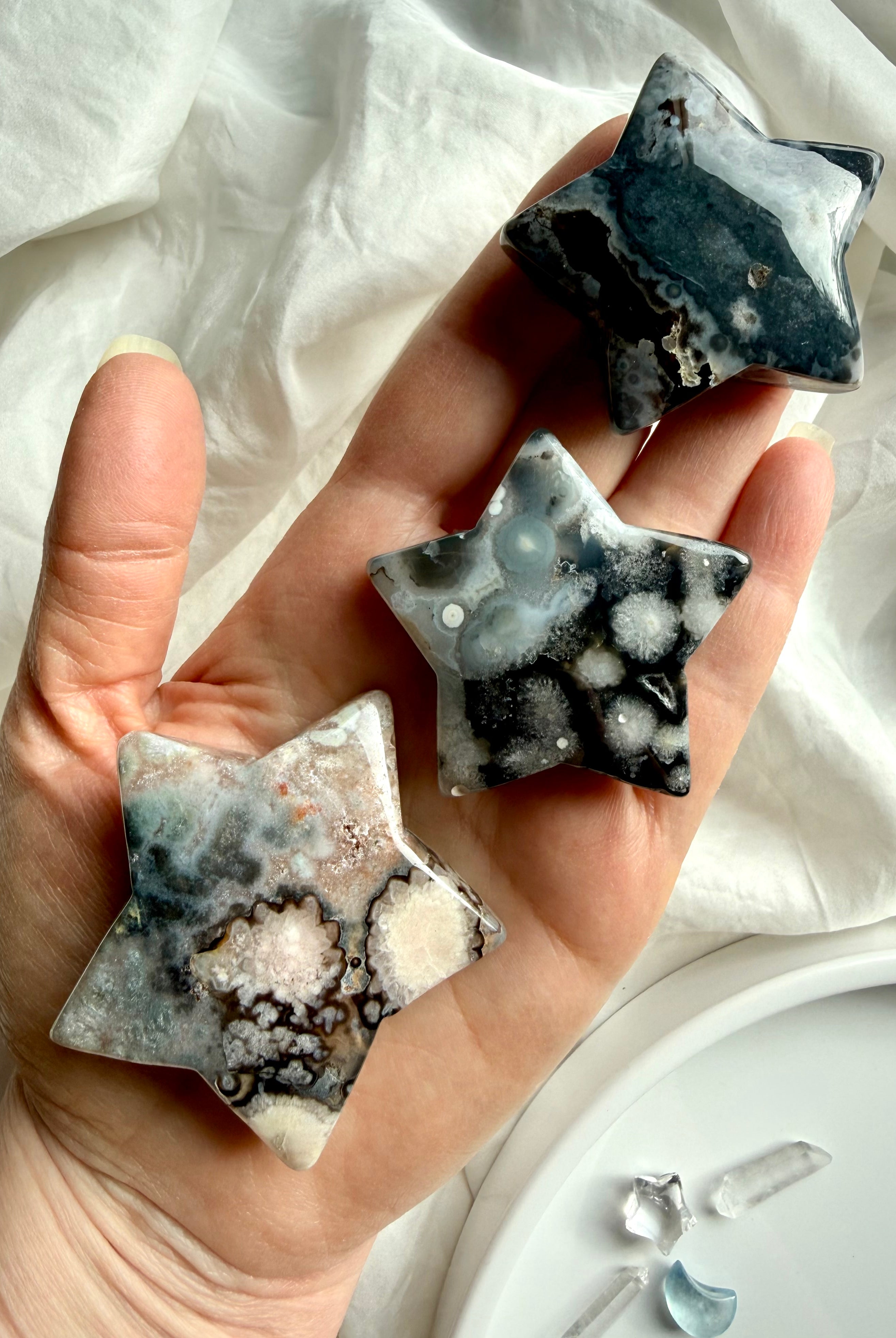 black flower agate moon and star carvings held in hand showing contrast of white blooms and dark agate base