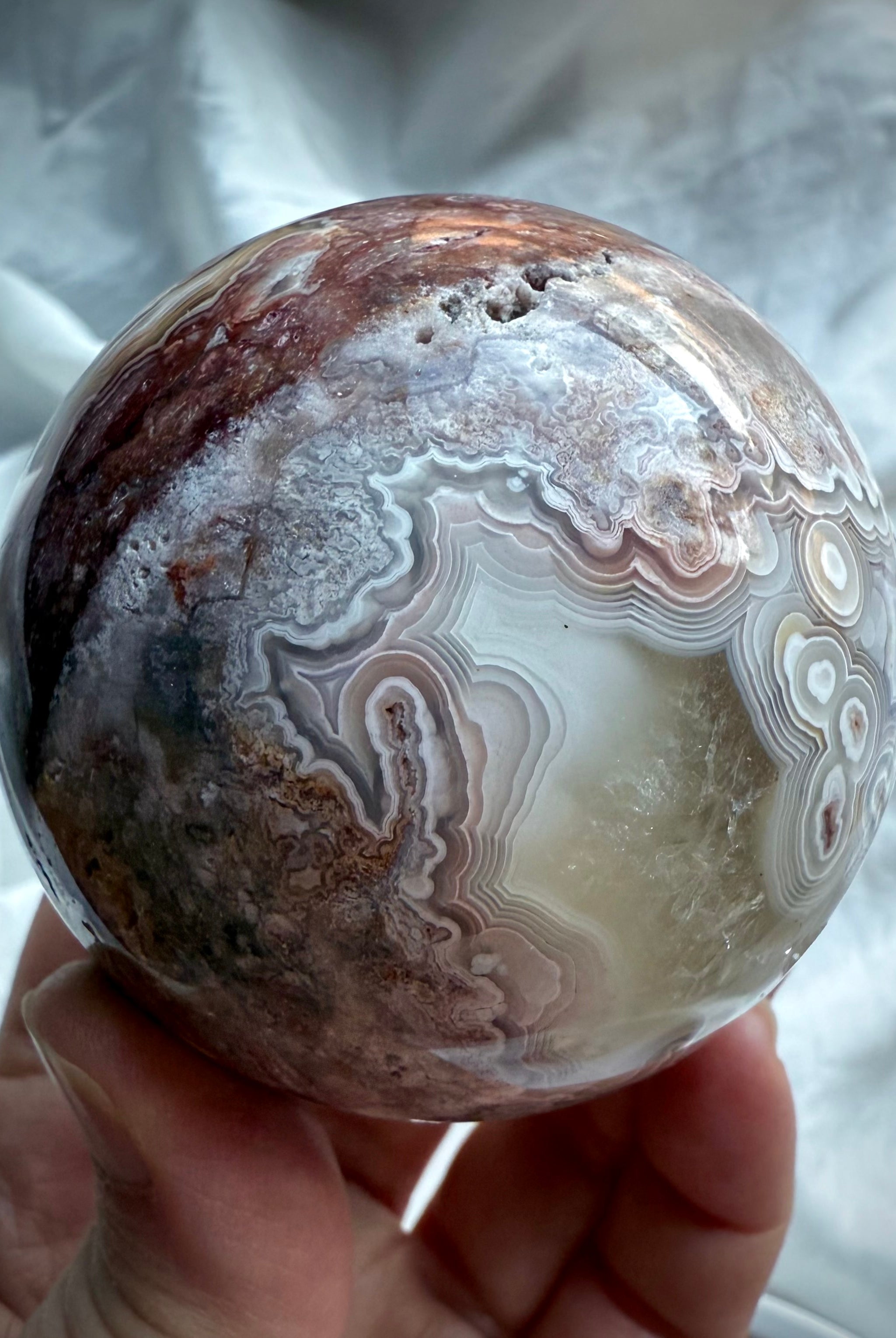 Banded agate sphere with soft purple and blush tones, featuring unique concentric ring formations