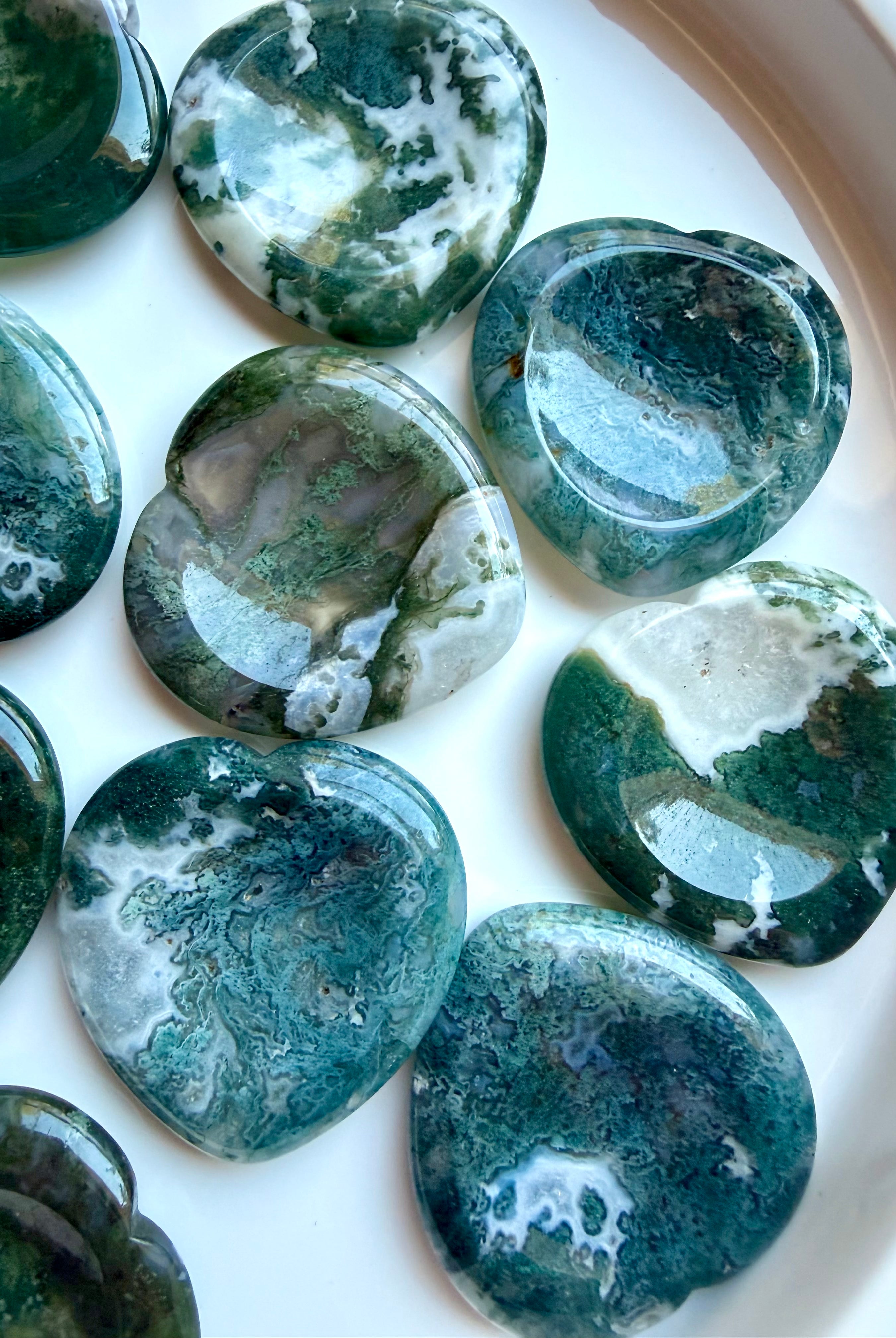 Closeup of Moss Agate heart worry stones with translucent quartz, mossy green inclusions and natural landscape patterns