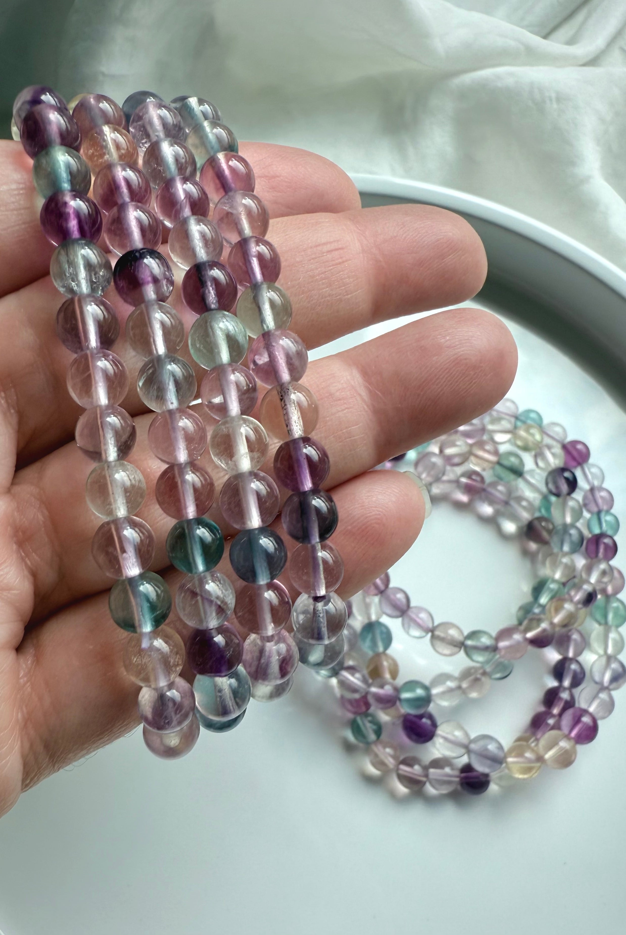 Fluorite bead bracelet shown on hand featuring polished translucent gemstones for focus & intuition