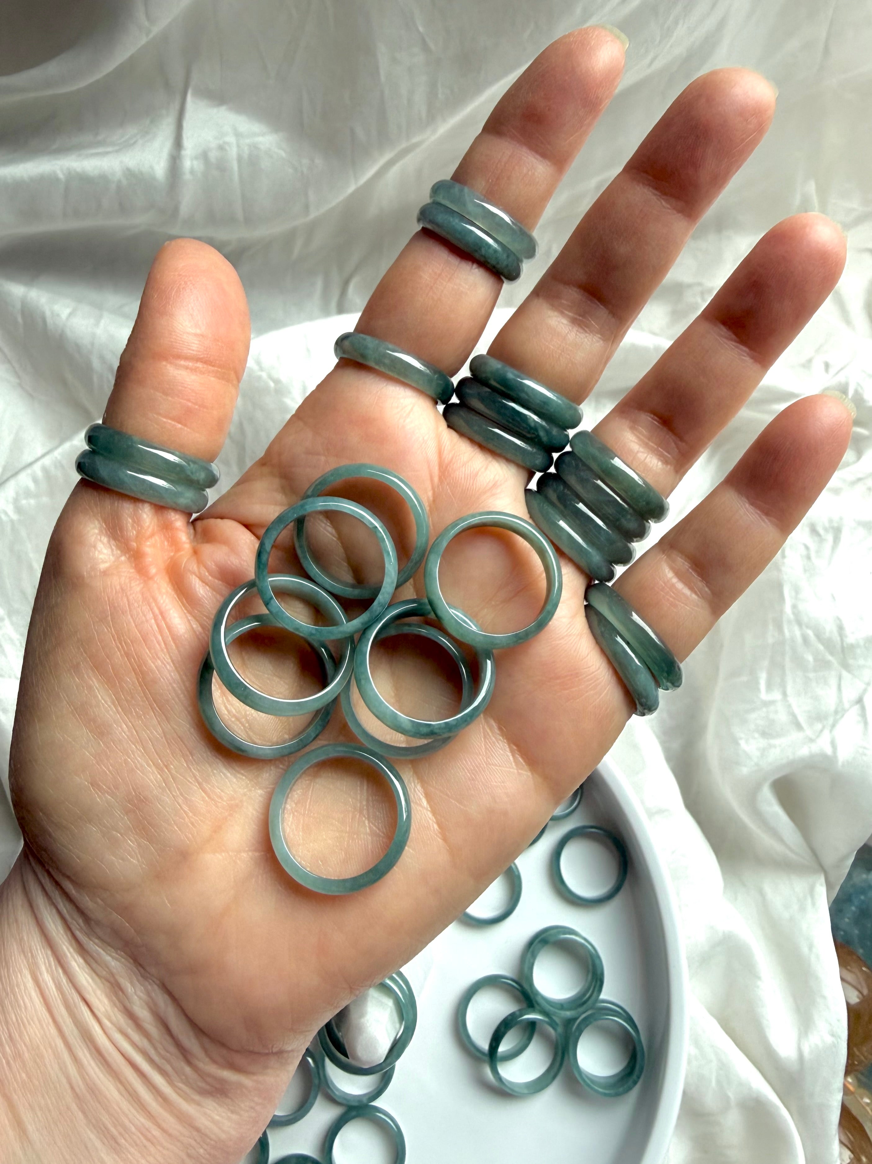 Natural Guatemalan jadeite band rings held in hand, rounded Blue Water jade crystal rings