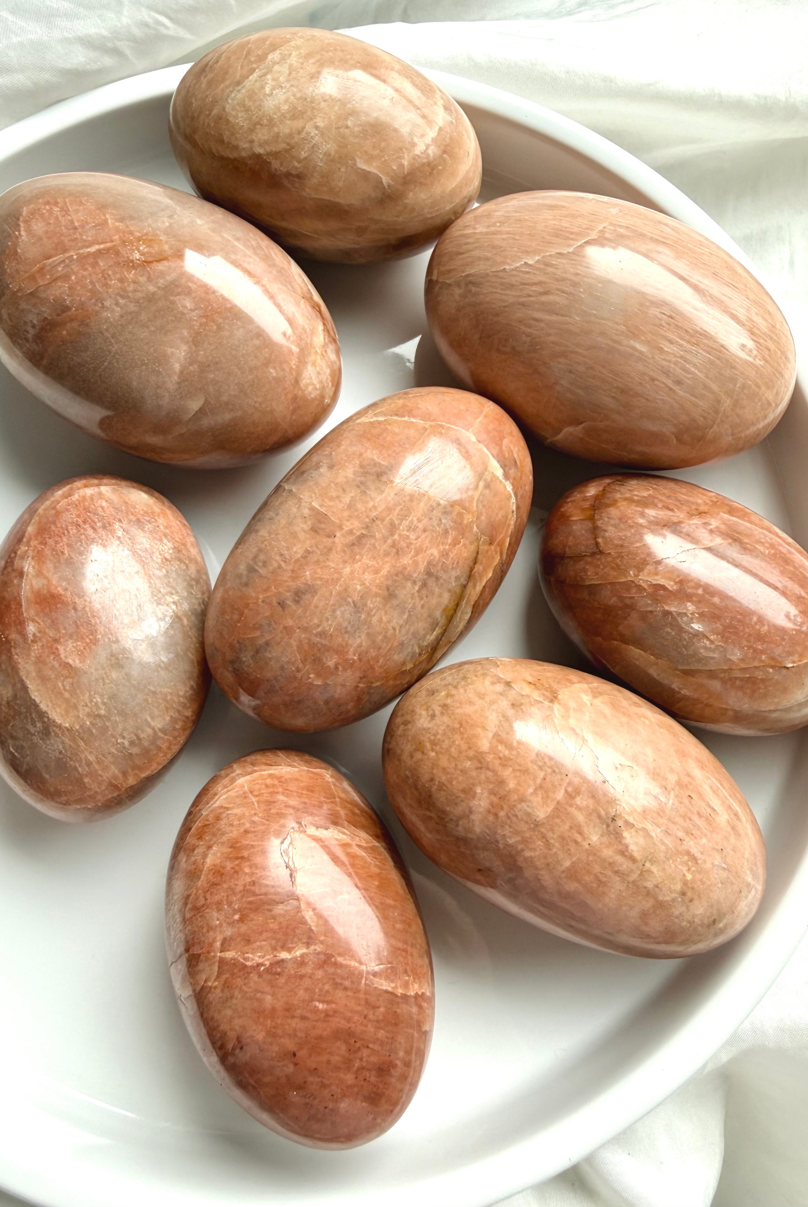 Polished Peach Moonstone palm stone with creamy peach tones and subtle feldspar shimmer