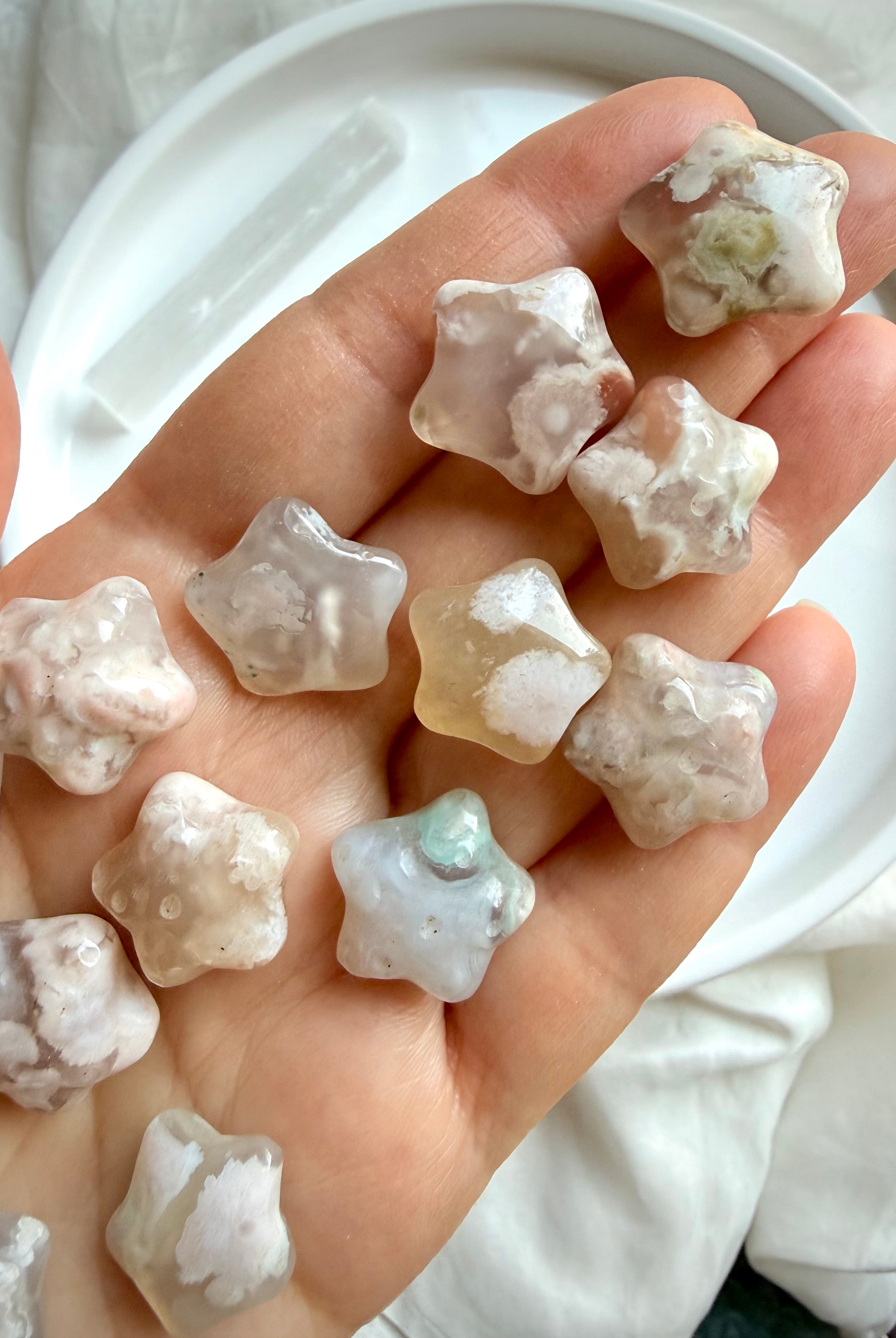 Flower Agate starfish carvings displayed in hand showing natural size, translucency, and unique blossom patterns