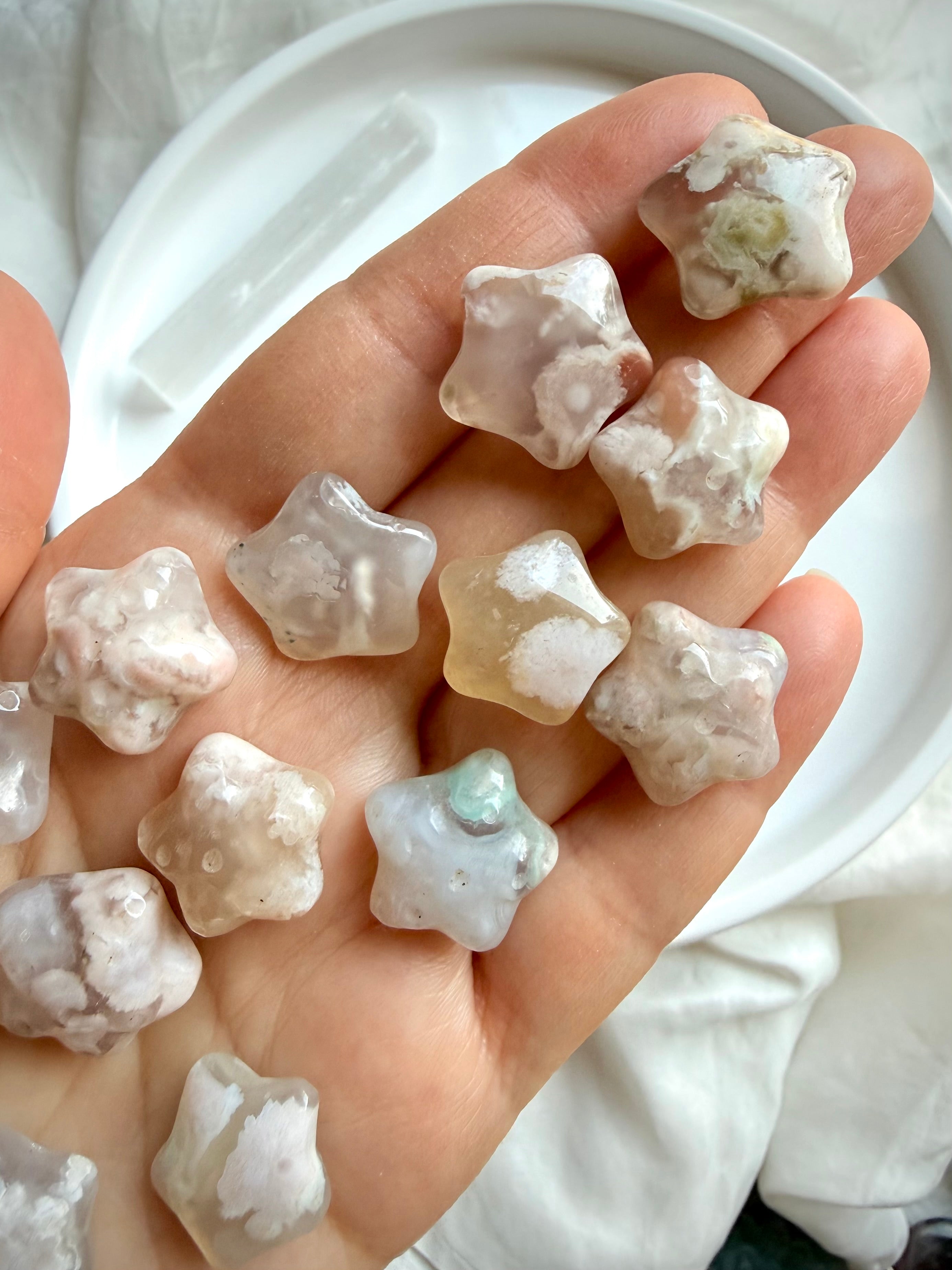 Flower Agate starfish carvings displayed in hand showing natural size, translucency, and unique blossom patterns