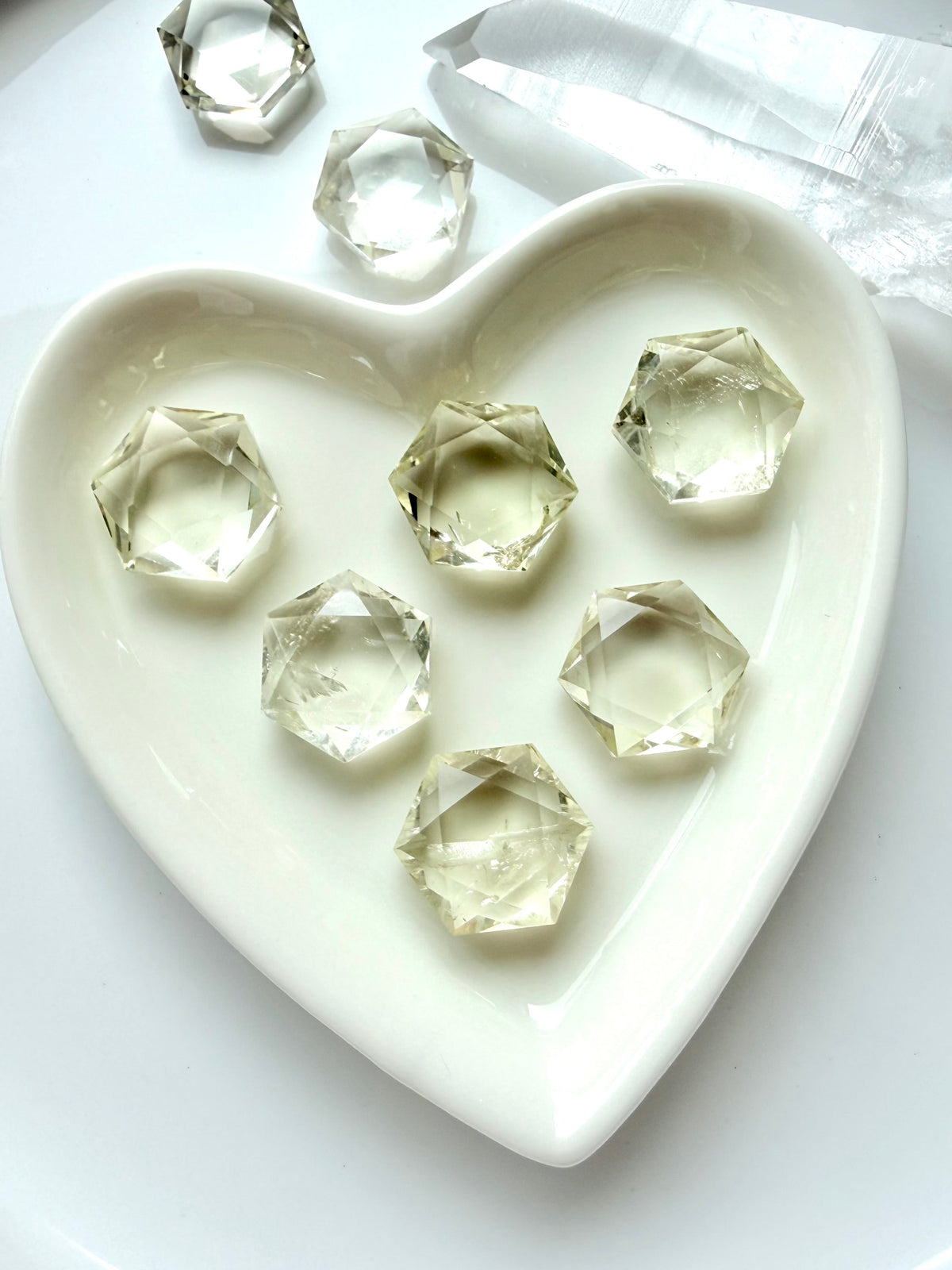 Mini Citrine hexagon crystals displayed in a heart-shaped dish with clear gemmy color and reflective facets
