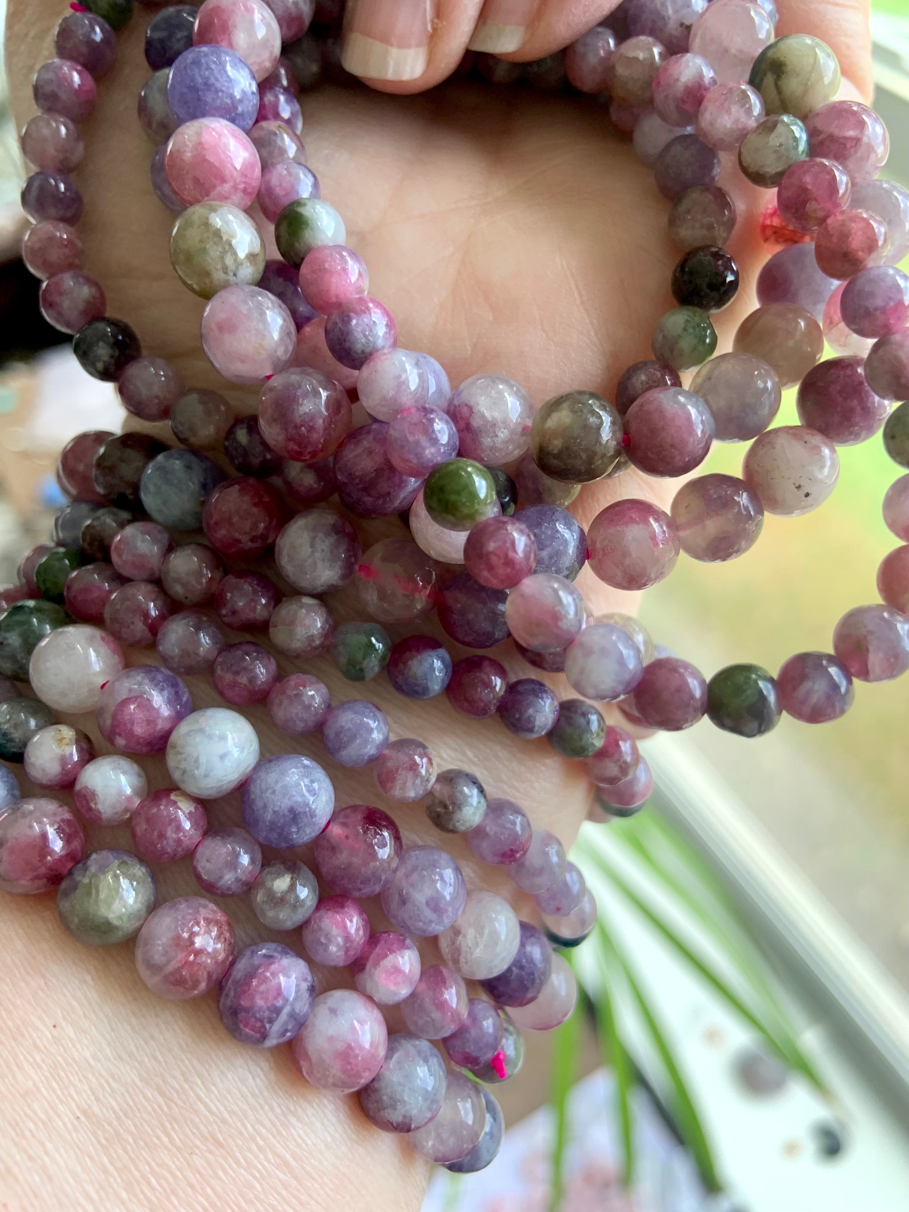 Detailed closeup of Watermelon Tourmaline & Lepidolite beads โ colorful heart chakra crystals showing natural variation in size, texture + hue