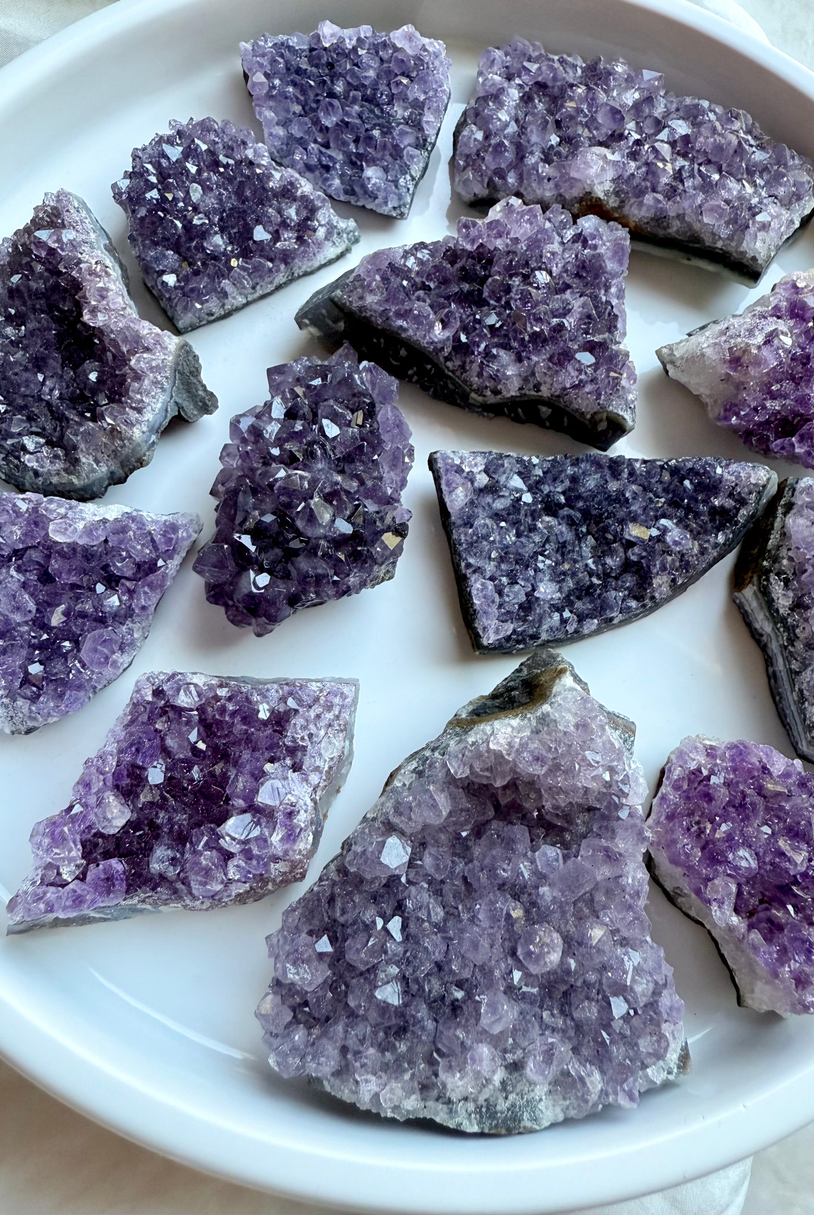 Angled view of amethyst geode clusters on white, sparkling purple crystals. Crown Chakra Healing stones for peace & clarity.