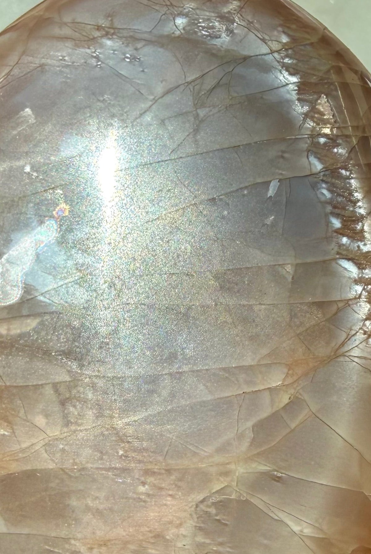 Close up view of Rainbow Peach Moonstone freeform with luminous silver sheen, peach tones and colorful iridescent flashes