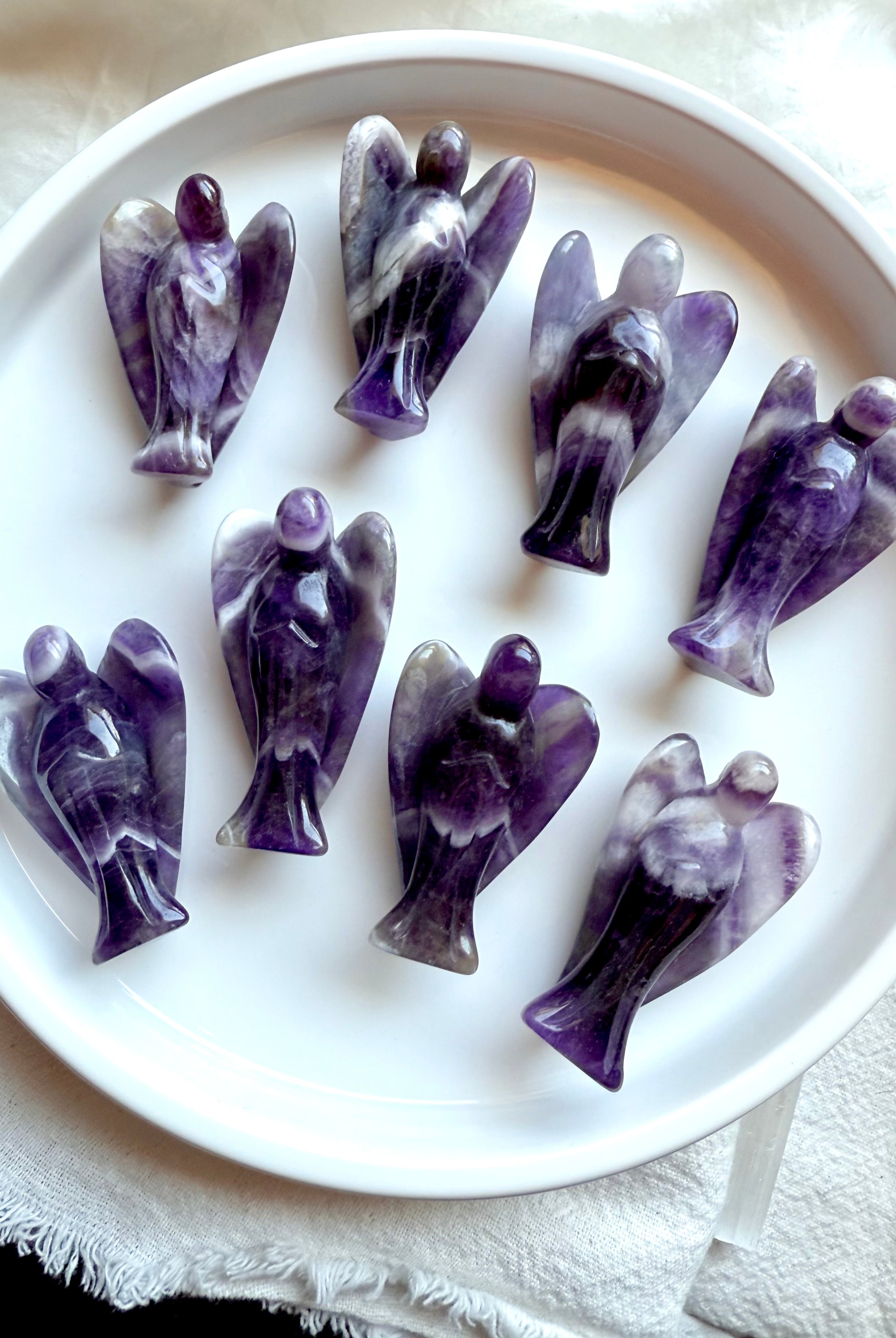 Group of eight hand-carved Dream Amethyst angel crystals from Zambia, showcasing bold Chevron Amethyst banding for peace, clarity, and spiritual protection.