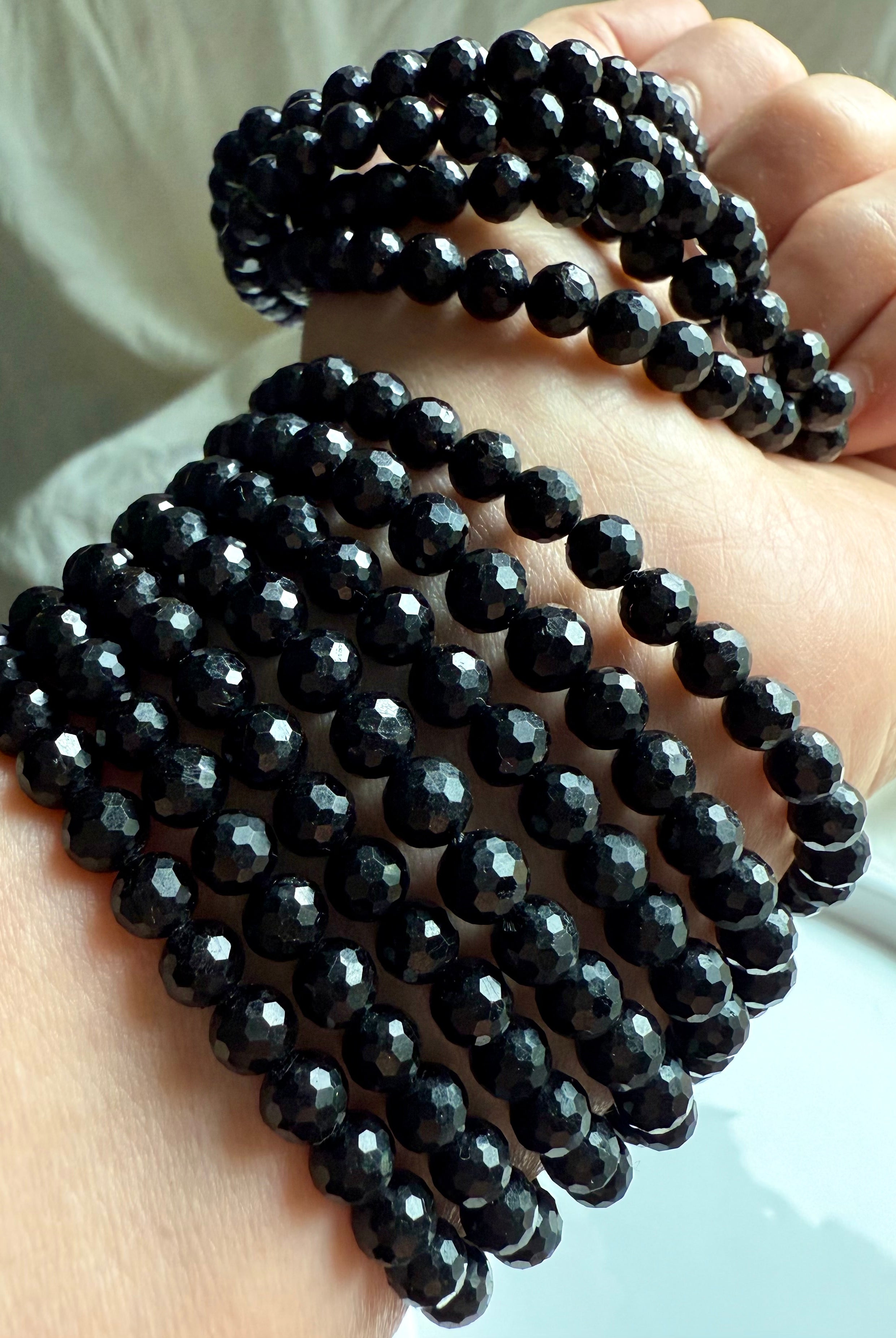stack of faceted black tourmaline bracelets wrapped around wrist for layered energy protection and EMF shielding