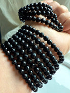 stack of faceted black tourmaline bracelets wrapped around wrist for layered energy protection and EMF shielding