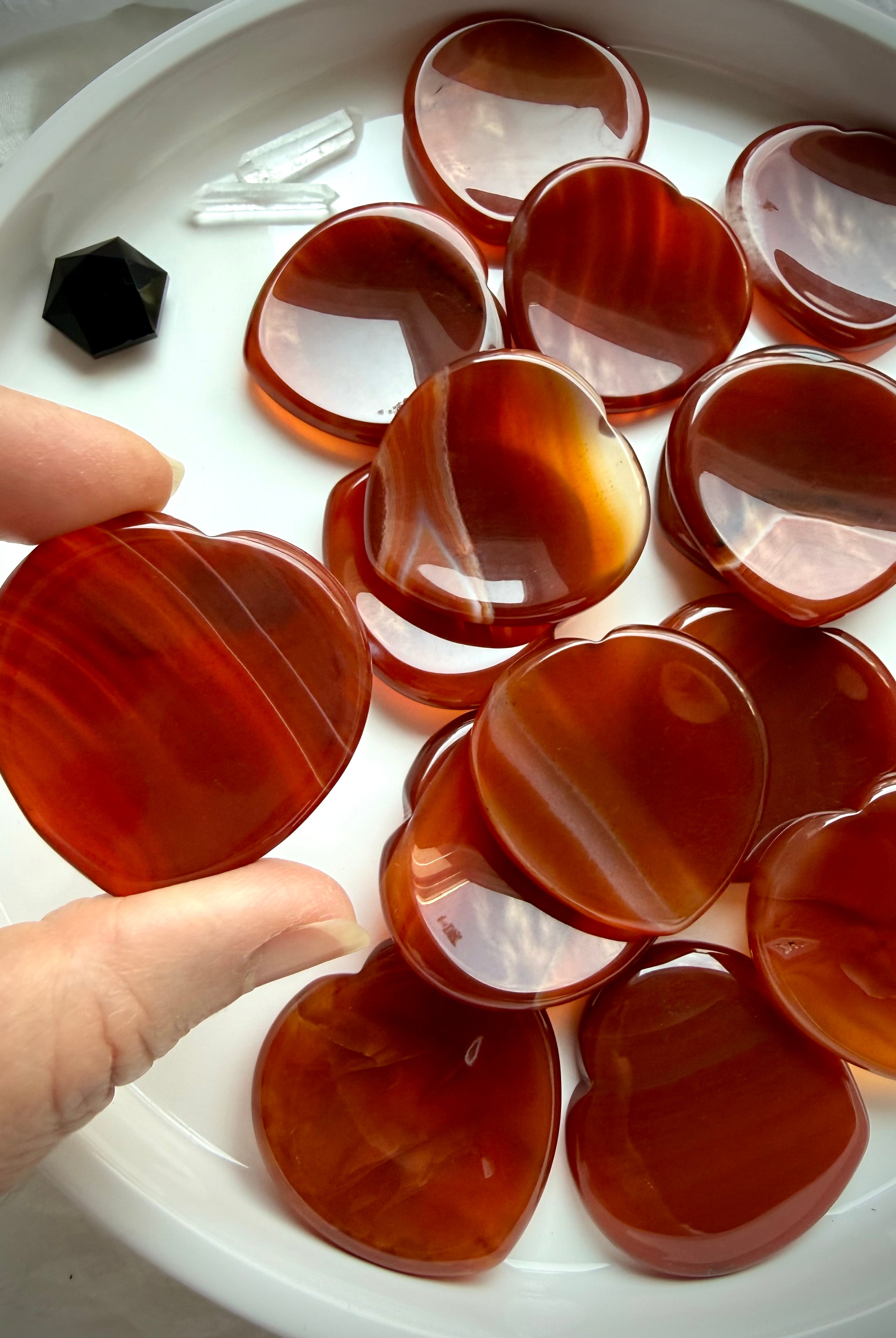 Carnelian heart worry stones showing glossy polish, translucent orange-red color and unique natural patterns