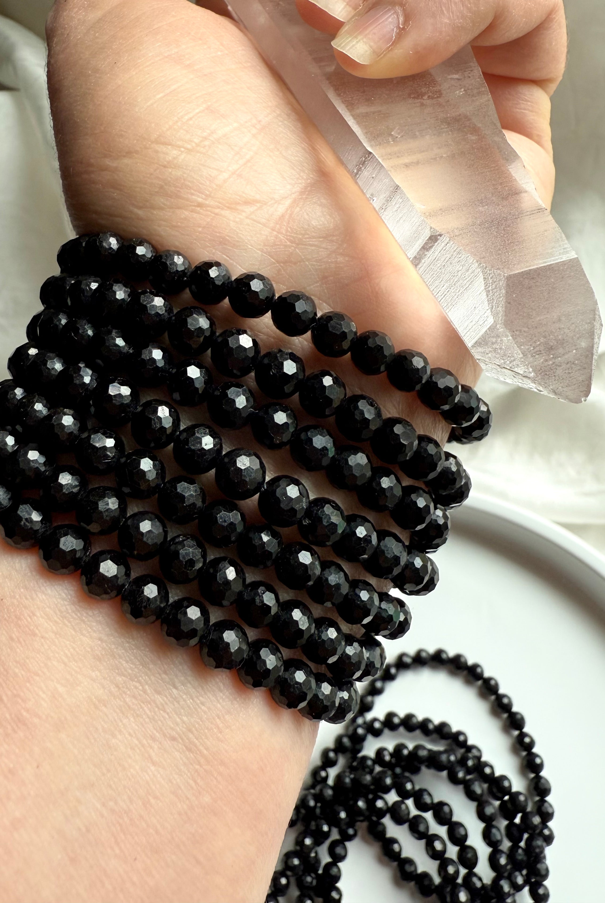clear quartz point and polished black tourmaline bracelets on wrist for grounding and energetic cleansing