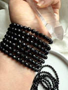 clear quartz point and polished black tourmaline bracelets on wrist for grounding and energetic cleansing