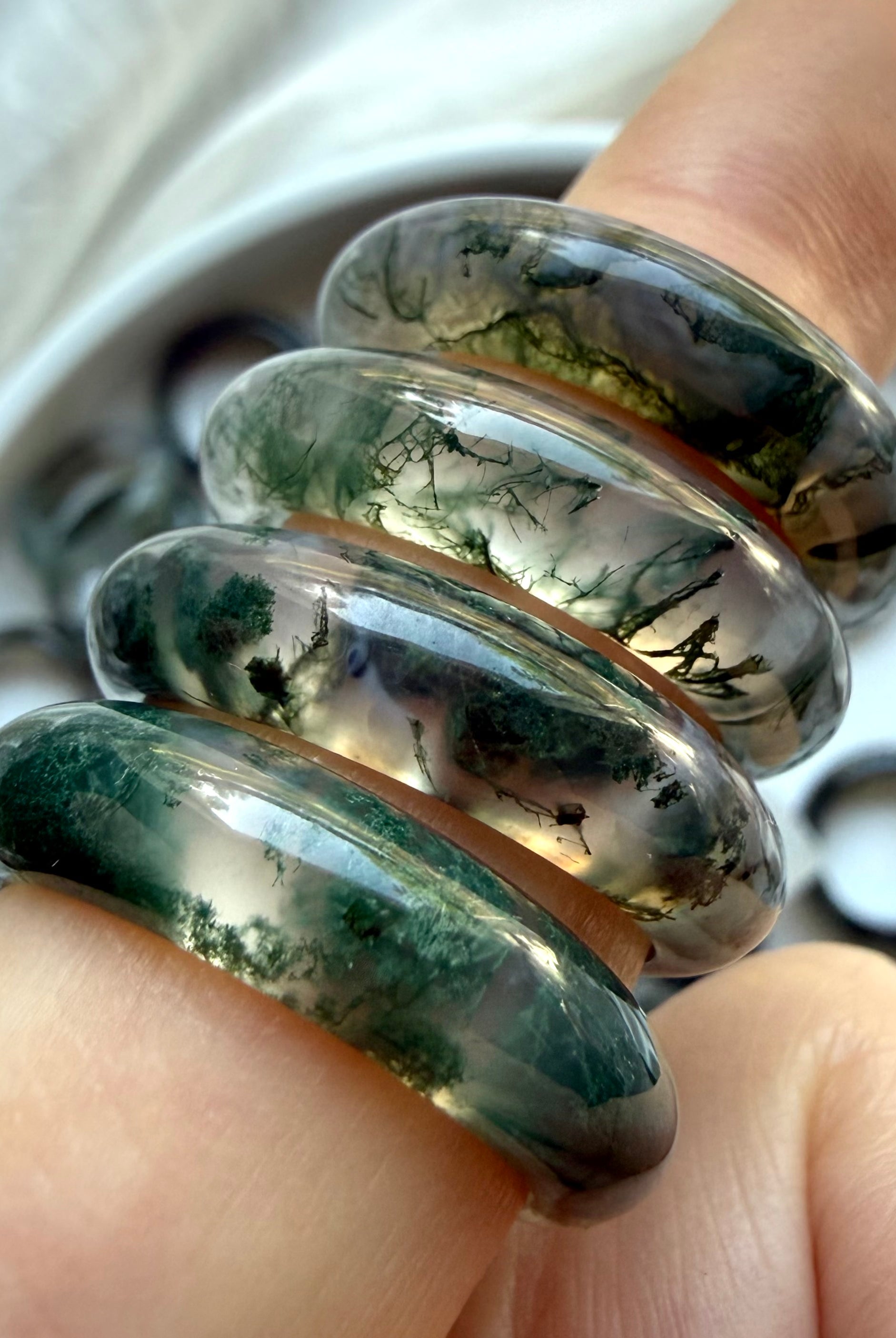 moss agate rings stacked on finger with visible green dendrites, grounding crystal jewelry for emotional balance and heart chakra energy