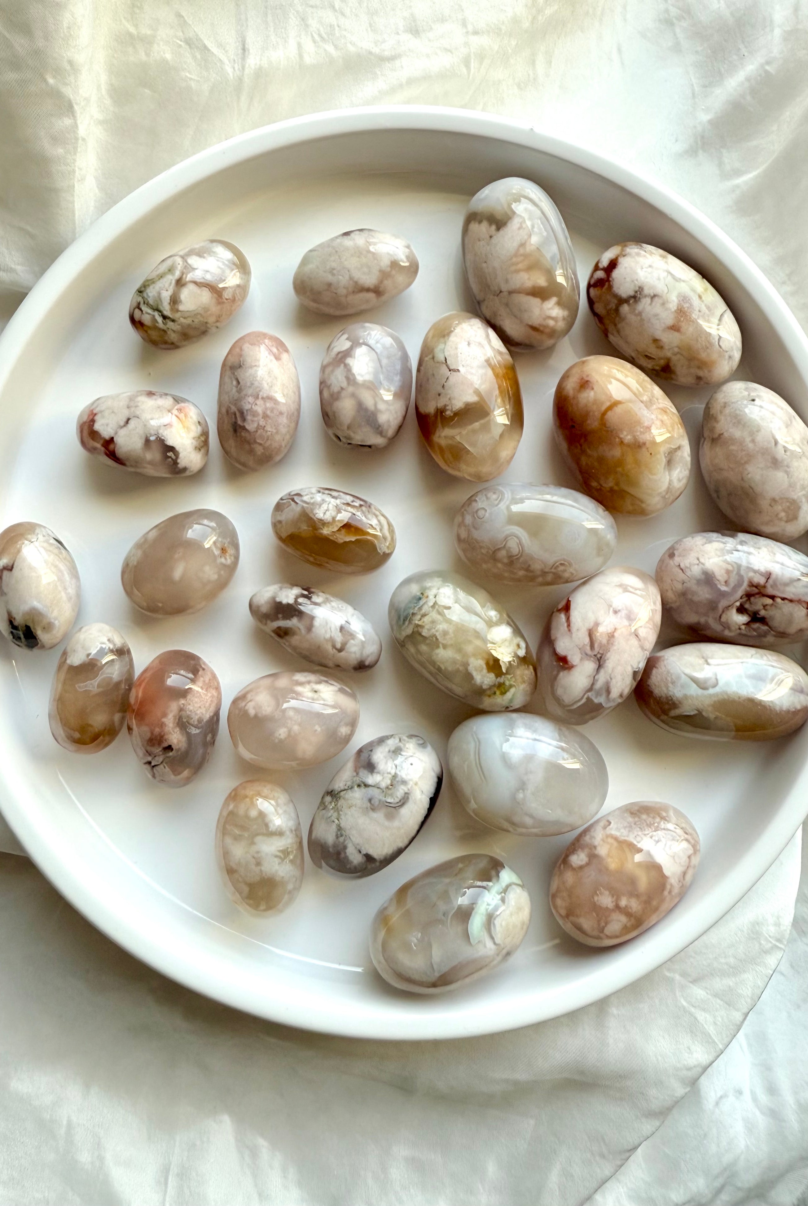 High quality pastel Flower Agate tumbled stones with beautiful color patterns shown on a white plate