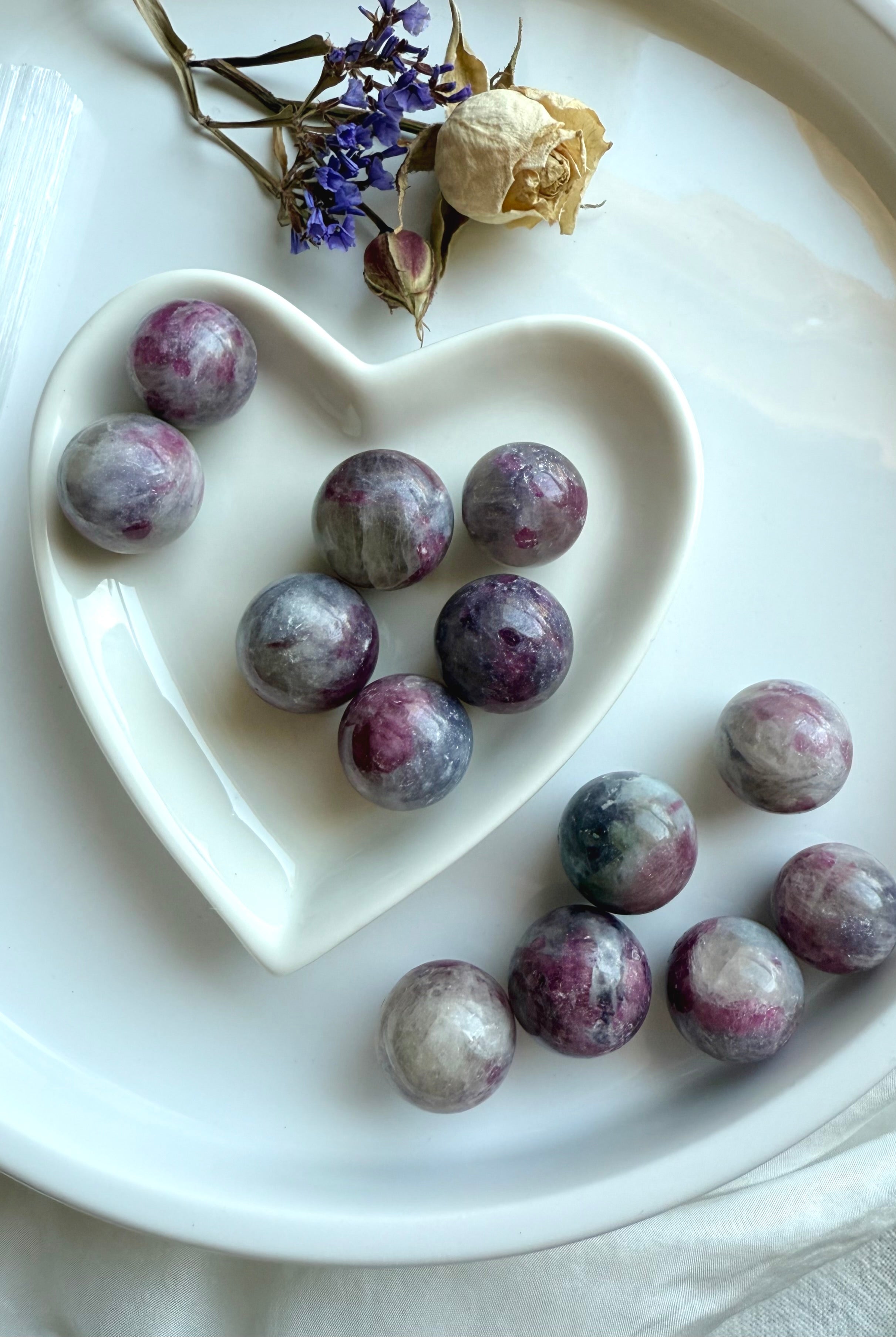Heart-shaped dish filled with Unicorn Stone spheres surrounded by dried flowers for a calming display