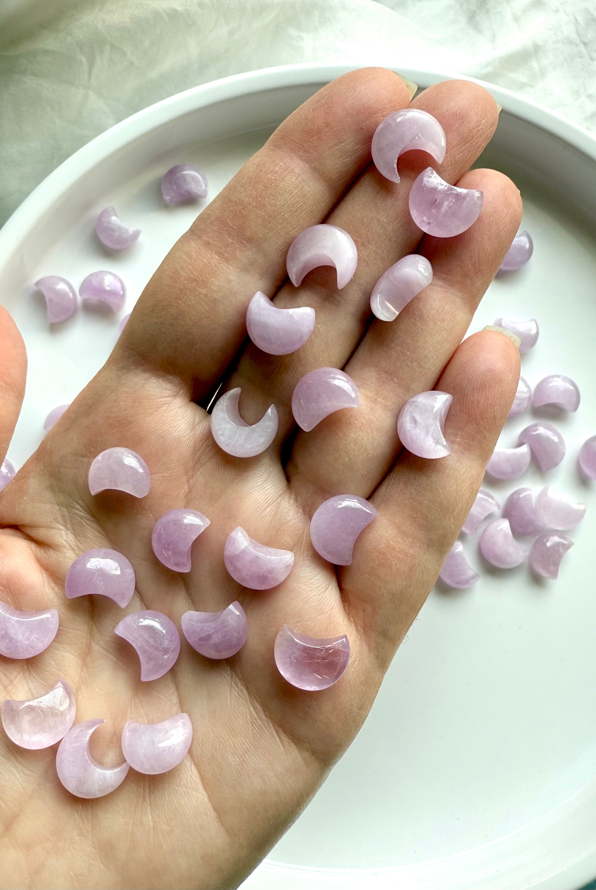 Mini Kunzite moon carvings shown in hand — small crystal moons for love, compassion & heart chakra support.