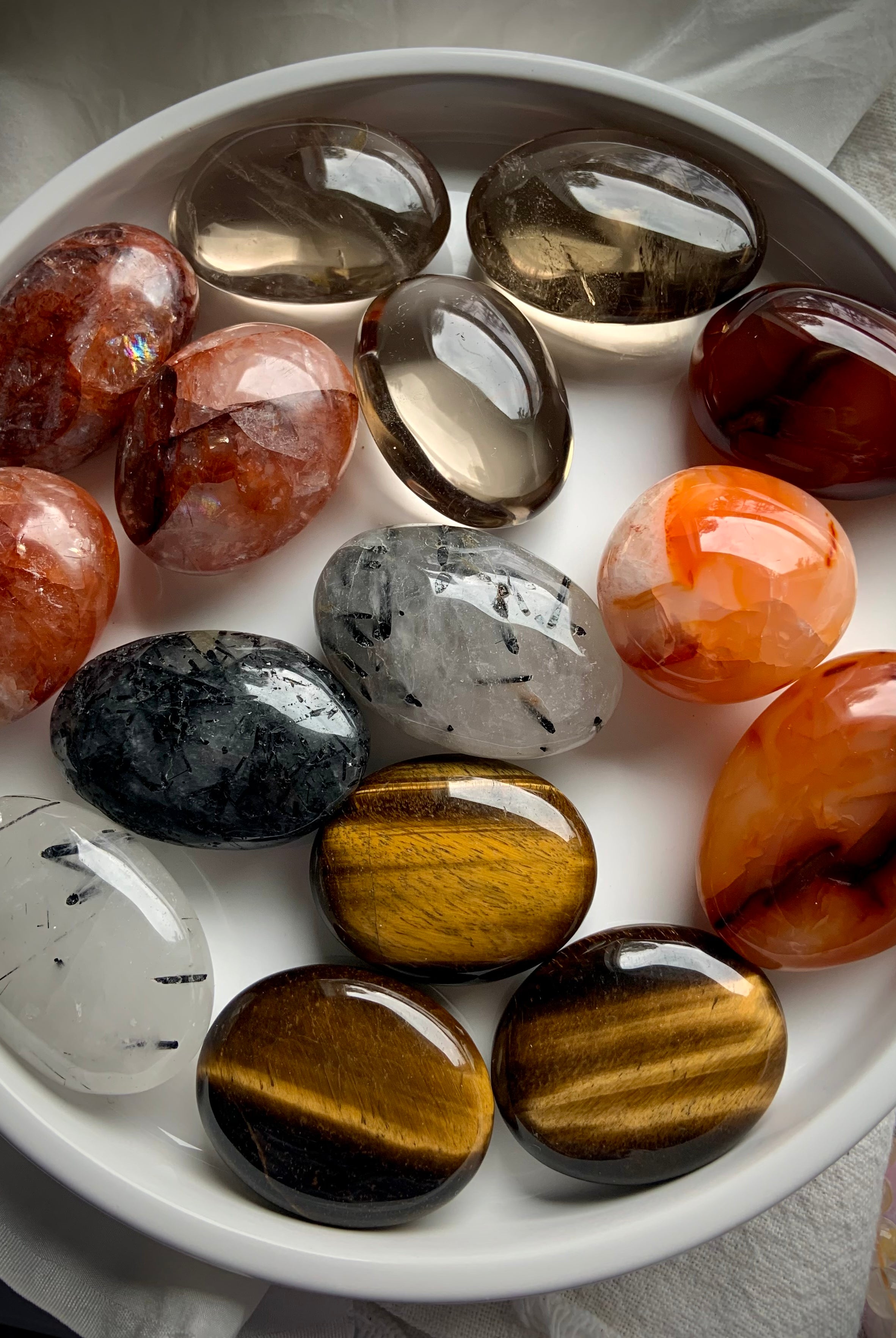 Full plate of chakra crystal palm stones in rich earthy tones — tumbled stones for grounding, energy alignment & spiritual empowerment.