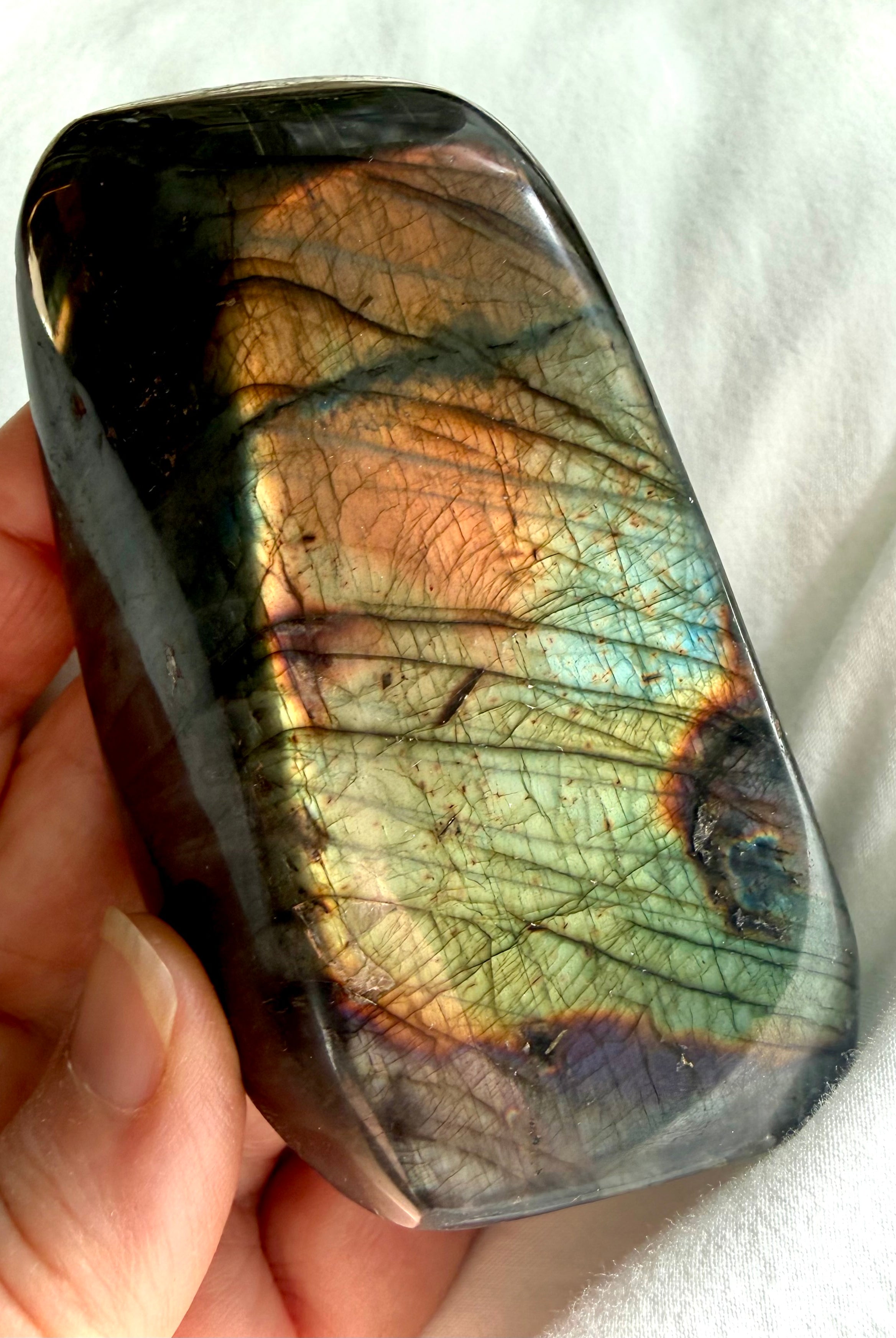 Reverse side of Labradorite freeform with softer green, aqua, gold, and copper flash across the dark polished stone