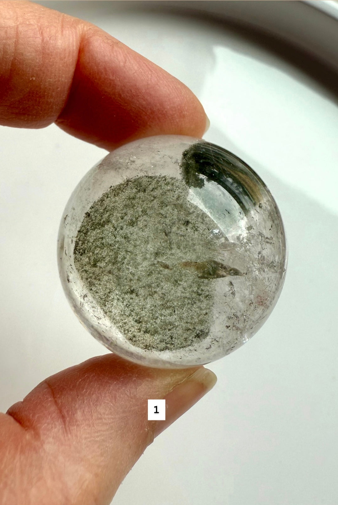 close-up of garden quartz sphere – clear crystal with moss-like inclusions for meditation