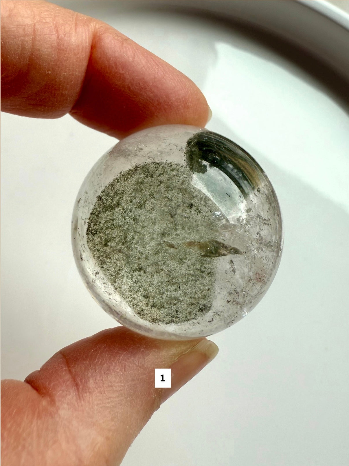 close-up of garden quartz sphere – clear crystal with moss-like inclusions for meditation