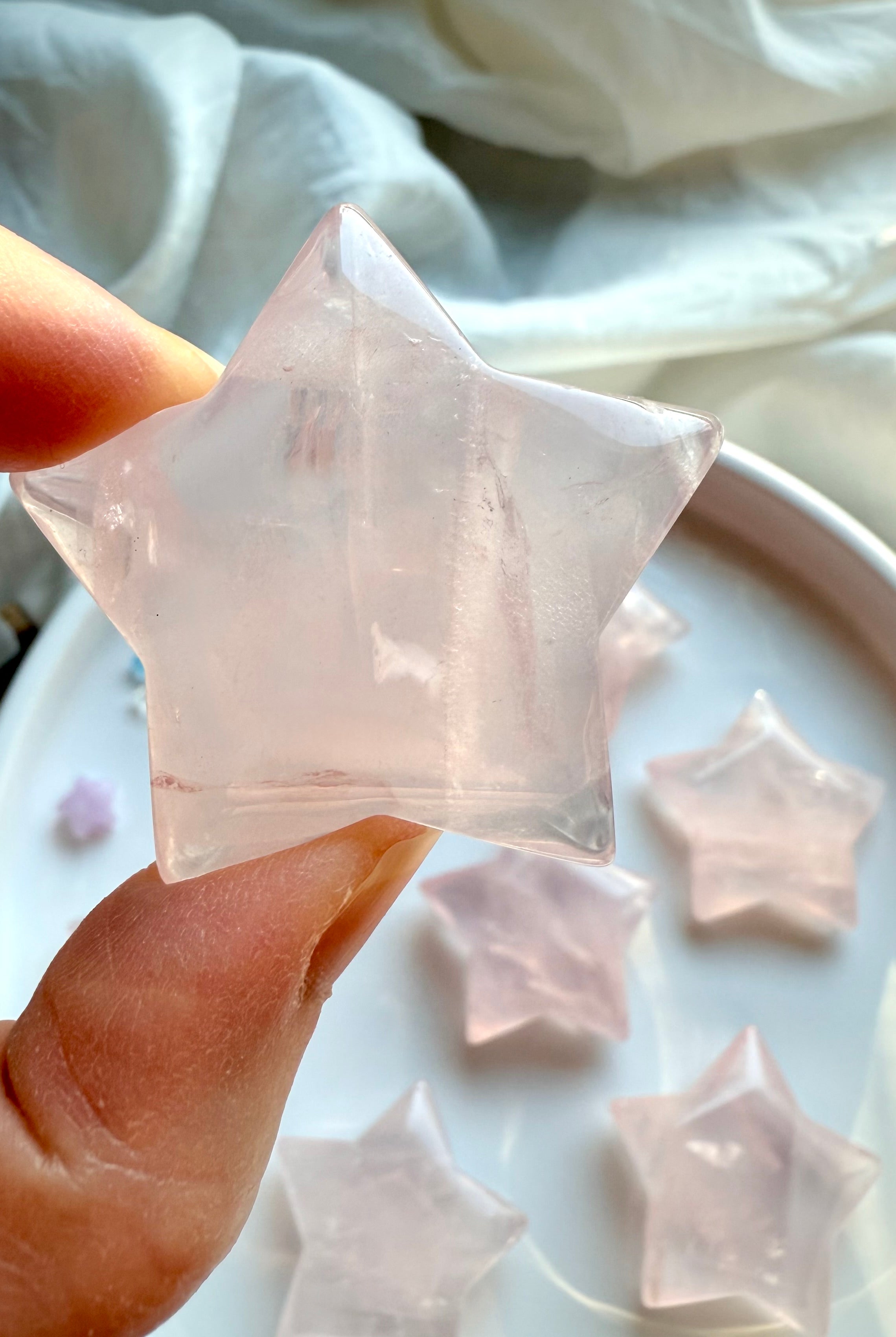 Rose Quartz star carving in hand showing natural variation and soft pink clarity — large Mozambique Rose Quartz star for love and heart chakra energy.