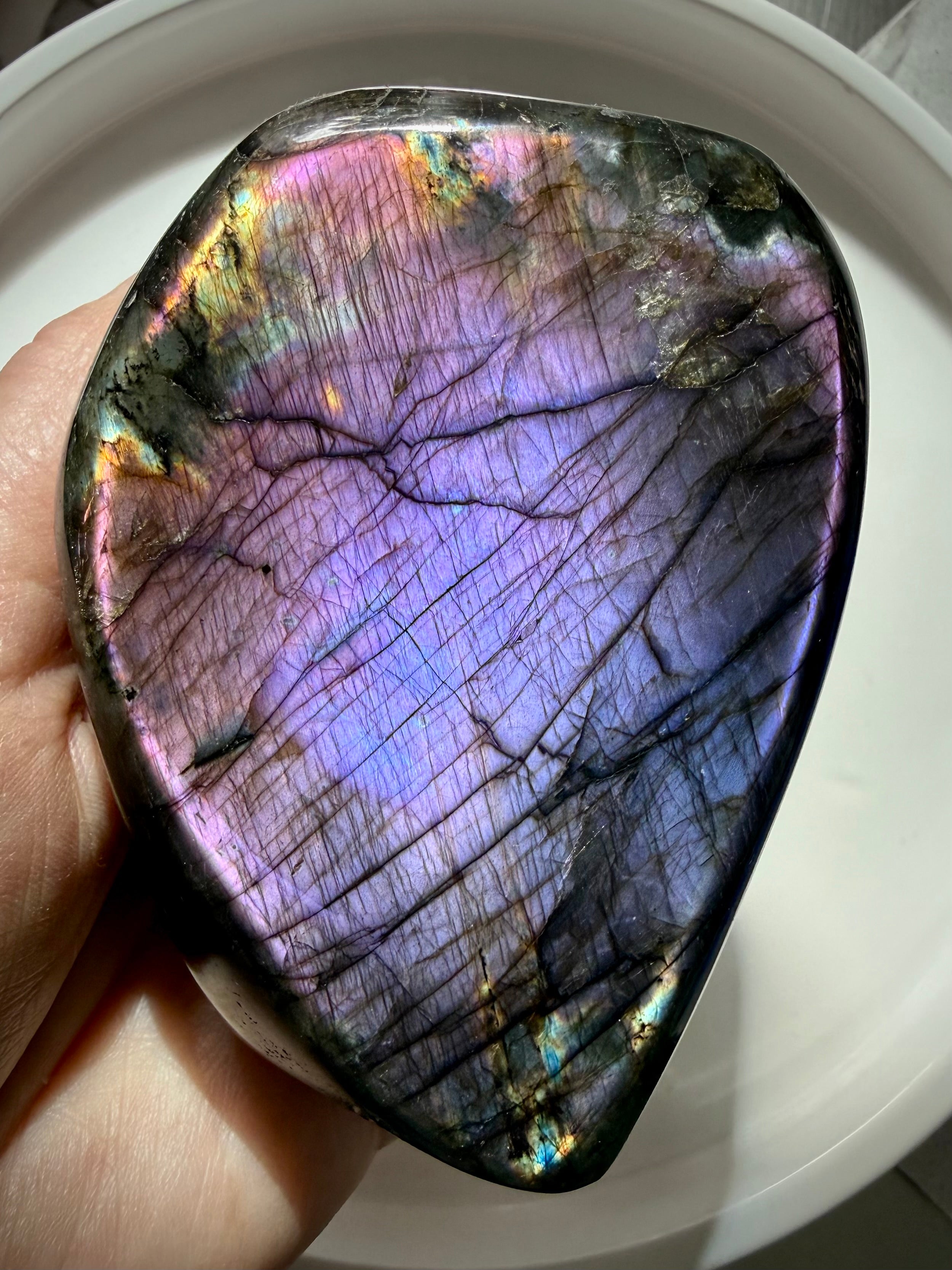 Purple Labradorite freeform held in hand with luminous violet, lavender and pink flash across the polished surface