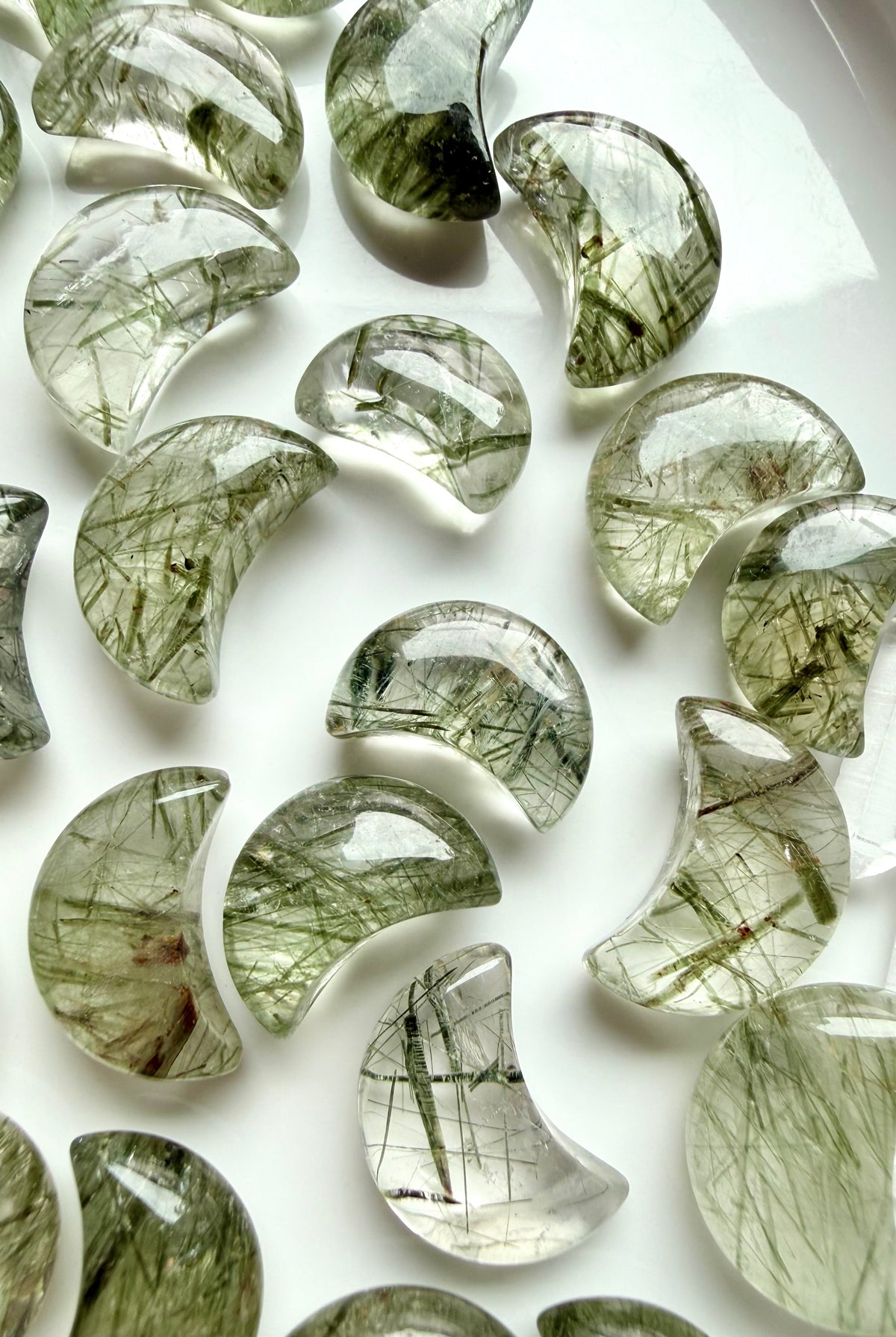Green Tourmaline Quartz moon carving held in hand, a Heart Chakra crystal associated with growth, abundance and renewal