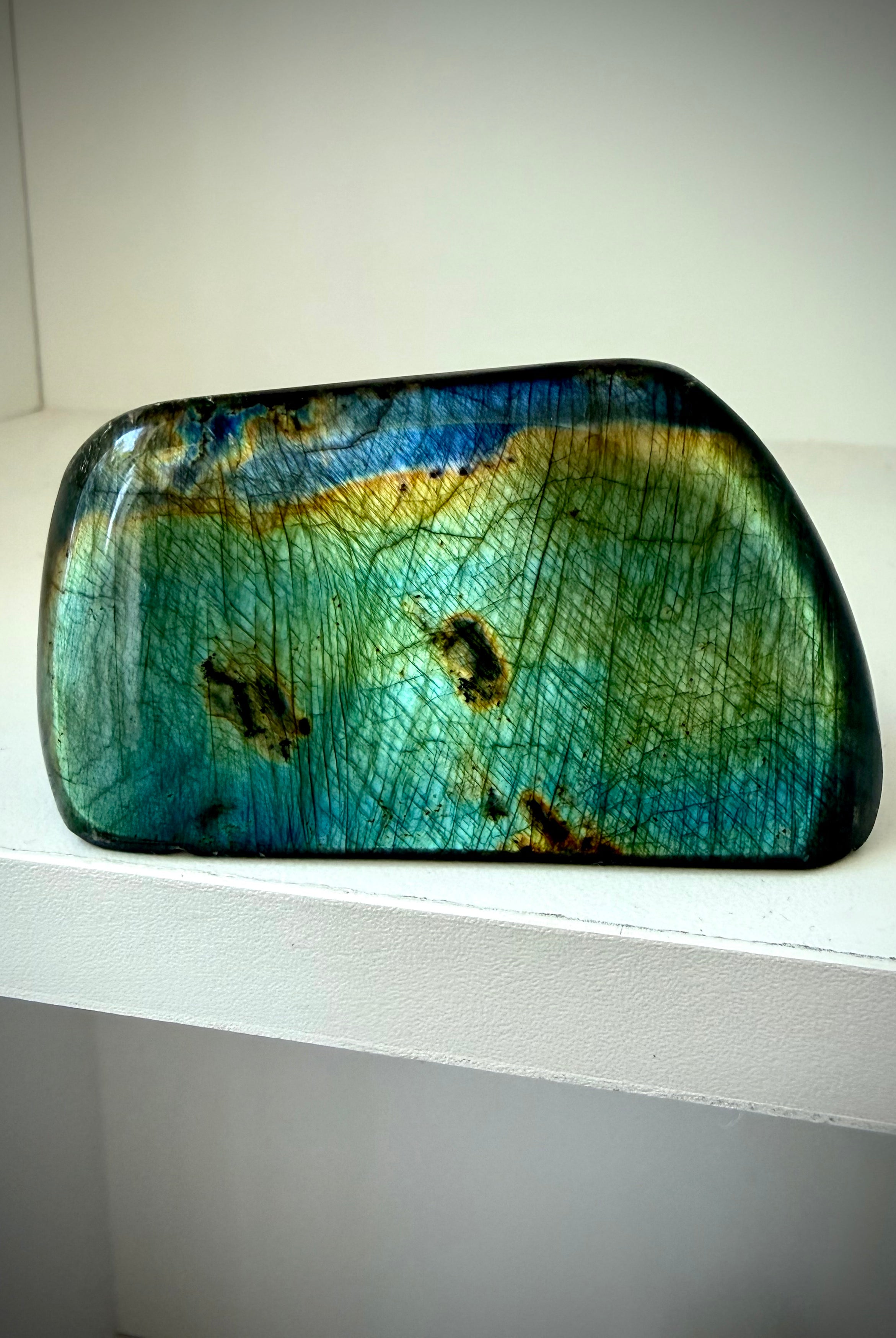 Polished Labradorite freeform with teal green and gold flash displayed upright