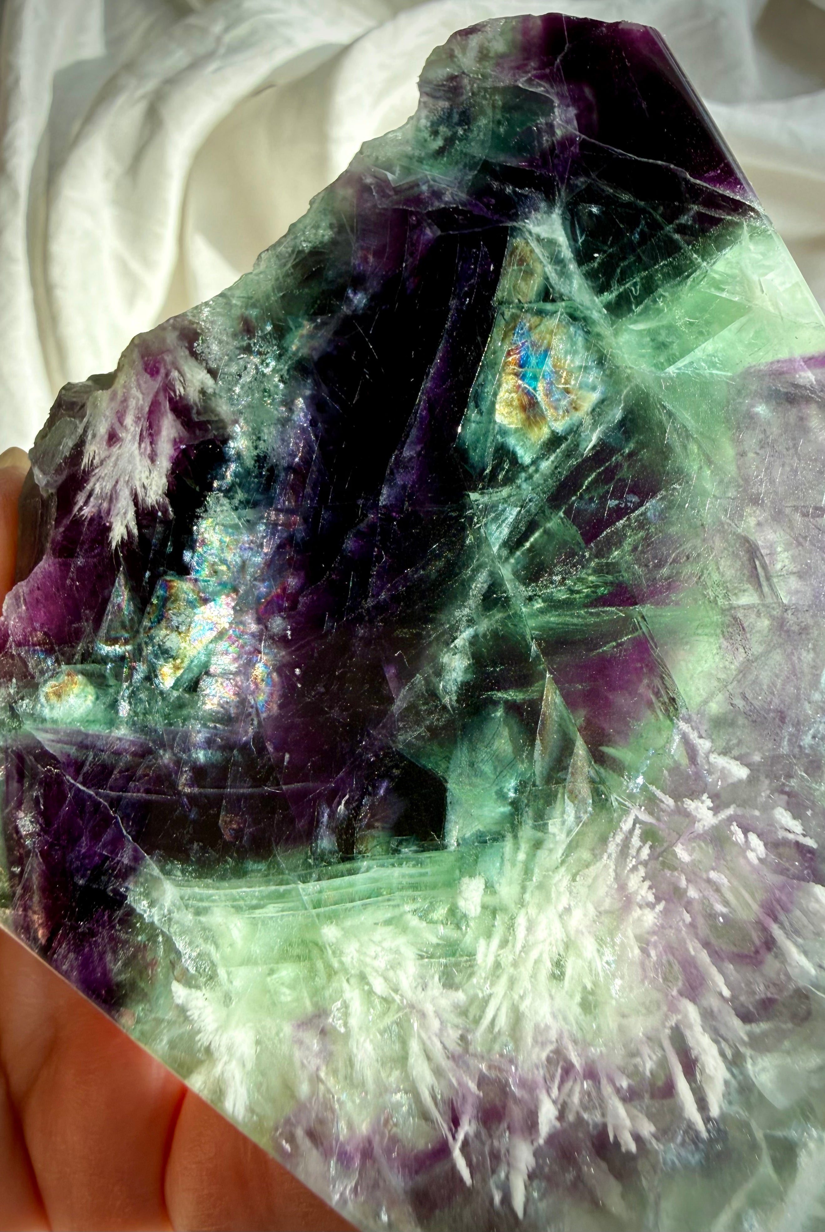 Close-up of green and purple fluorite slab showing rainbow internal flashes and white scolecite snowflake inclusions