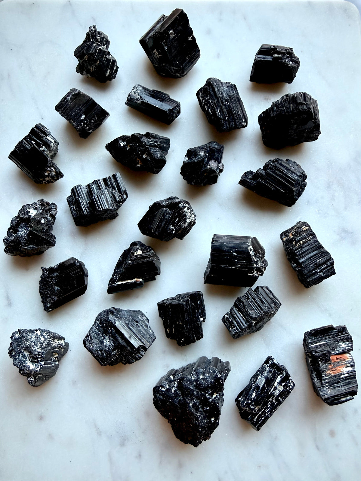 Raw Black Tourmaline chunks with glossy crystalline striations, natural matrix, and varied rough formations for grounding and protection