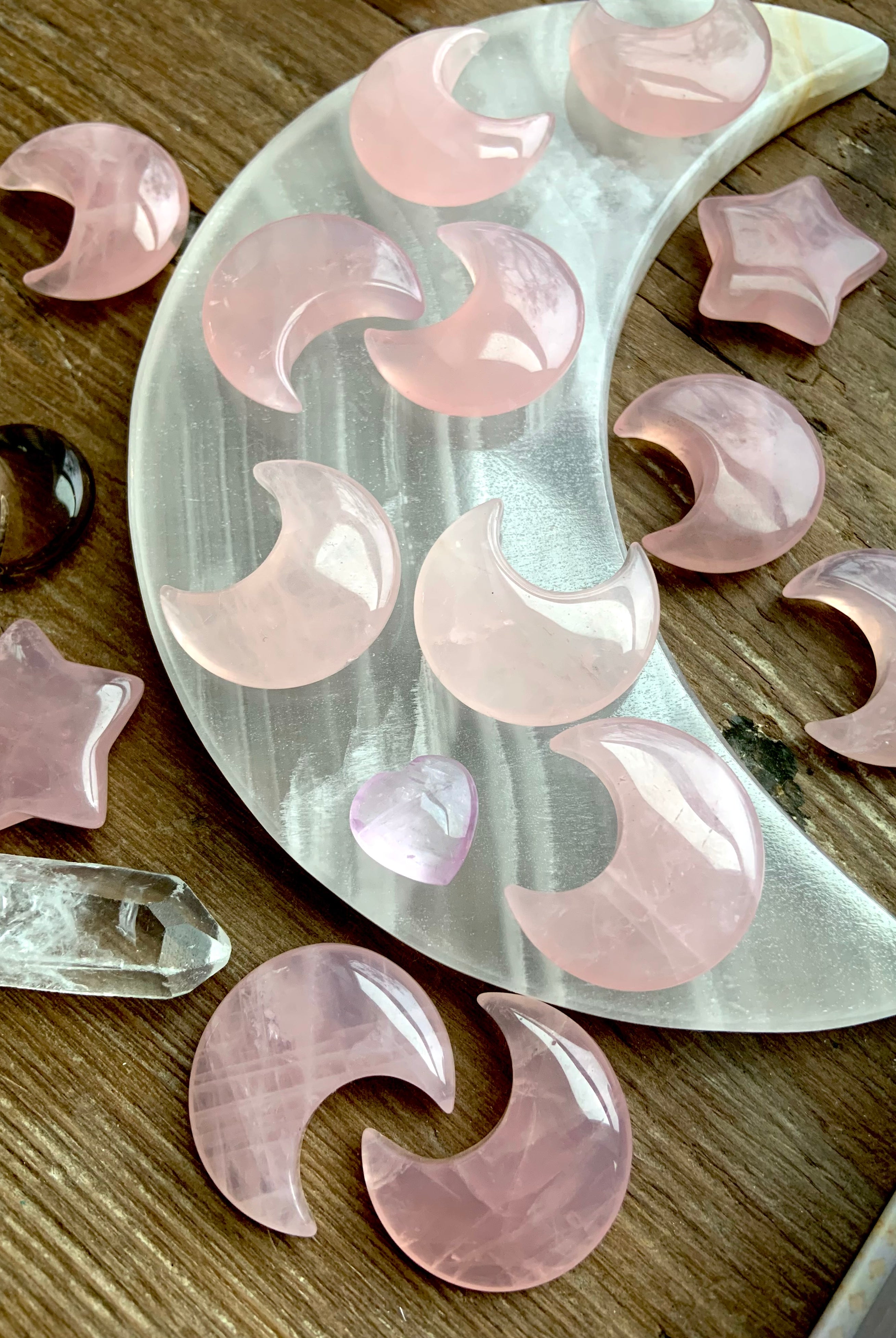 Angled view of rose quartz moons and stars on a white onyx moon plate with quartz points