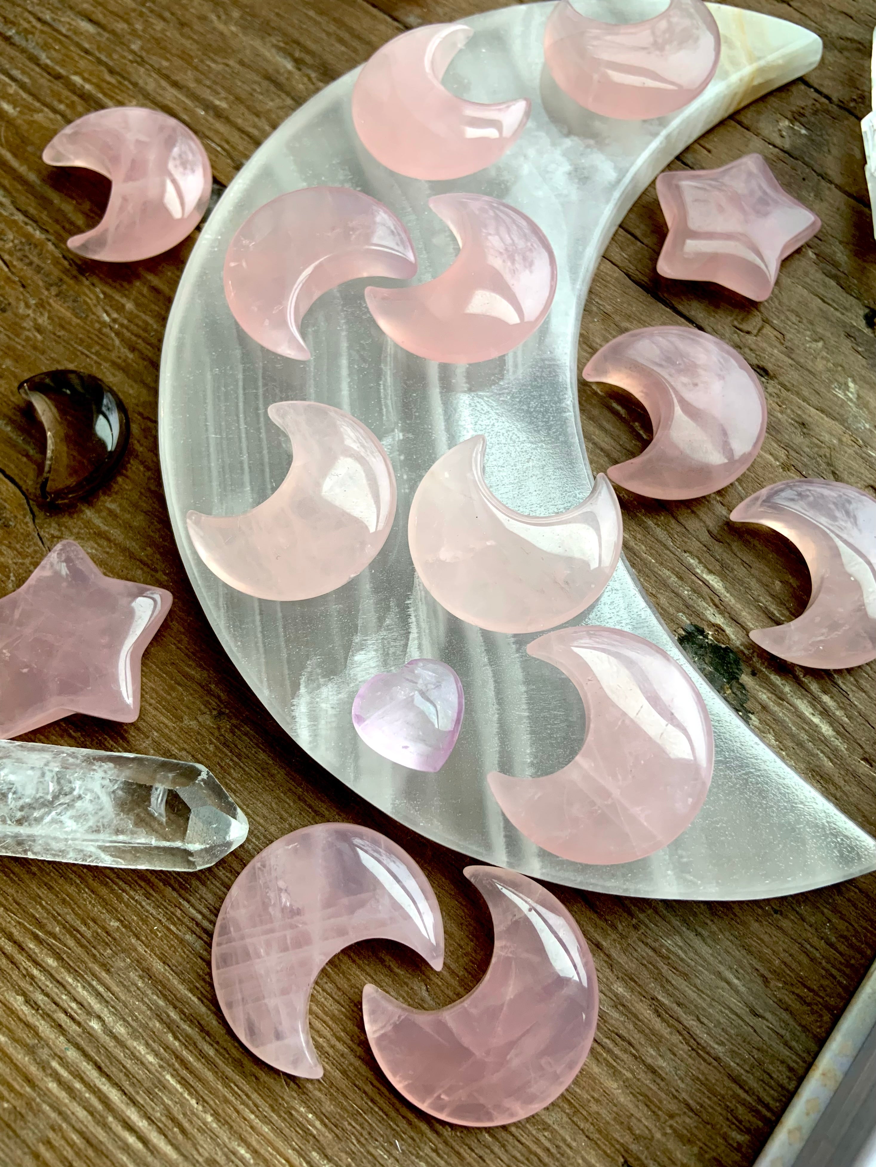 Angled view of rose quartz moons and stars on a white onyx moon plate with quartz points
