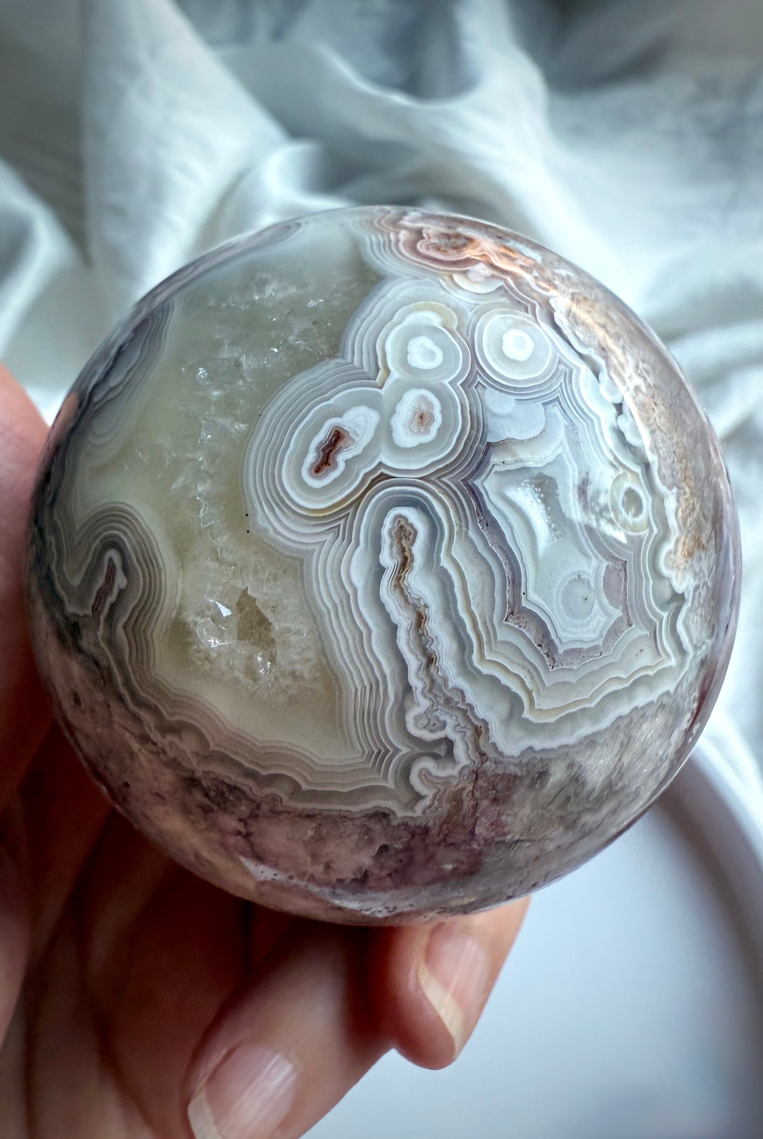 Orbicular Crazy Lace Agate sphere with layered concentric patterns and earthy tones of plum, beige, and charcoal