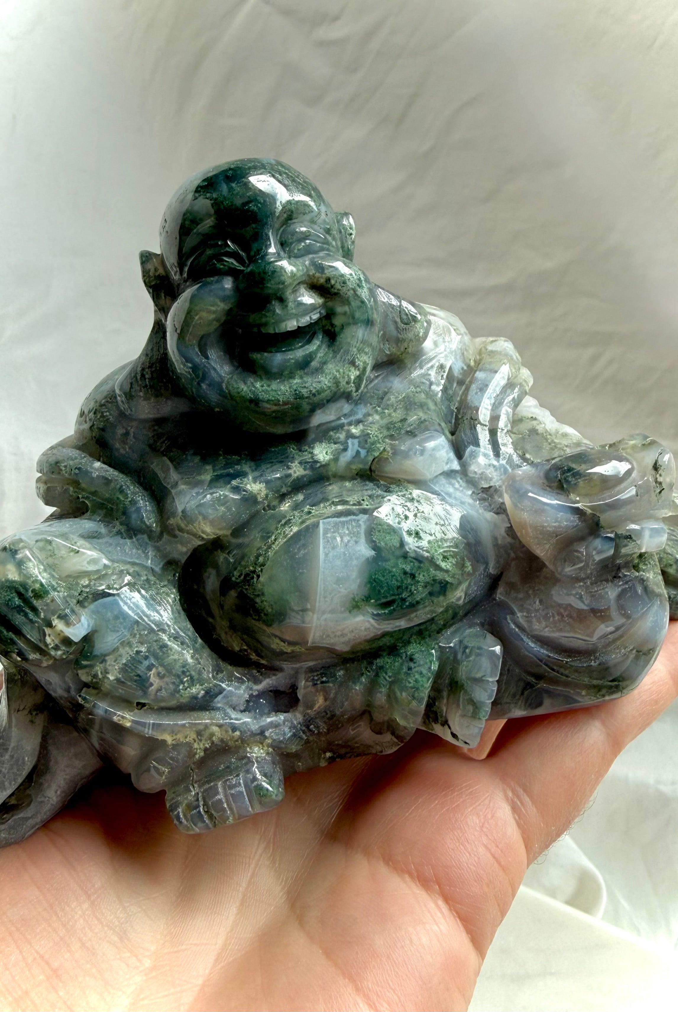 Large Moss Agate Laughing Buddha statue held in hand showing size and polished details
