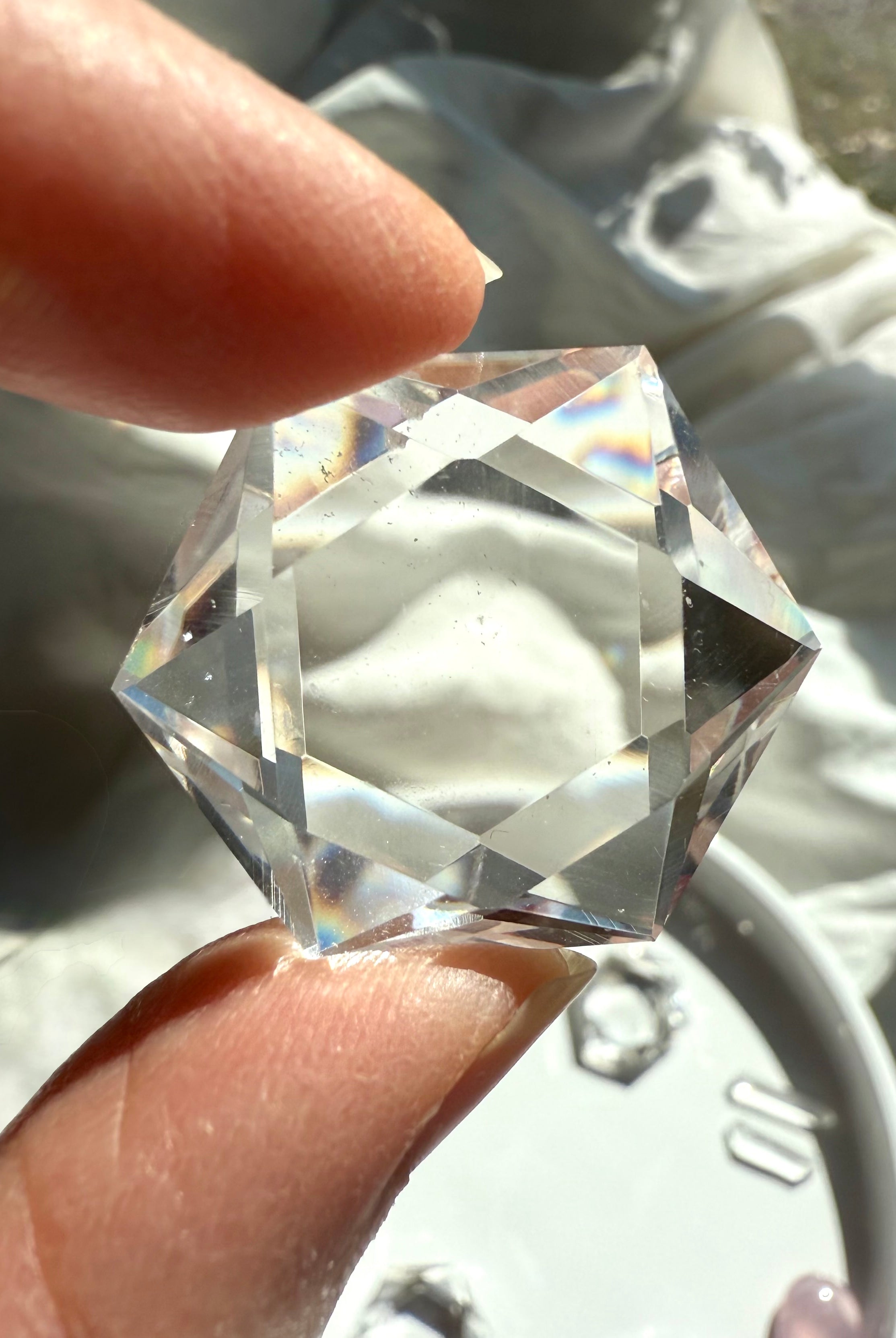 Closeup of faceted Clear Quartz hexagon held to the light, showing water-clear transparency and gemmy polish
