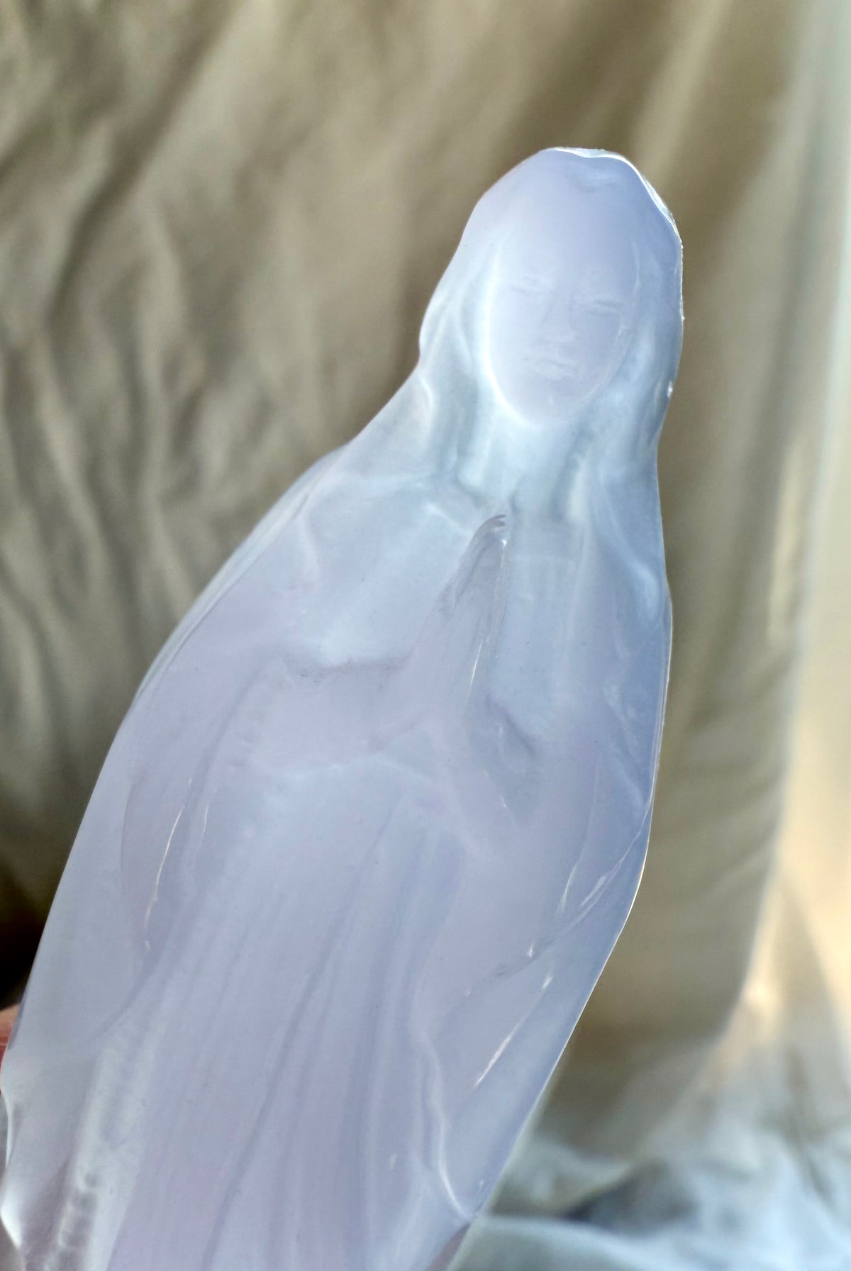 Close view of Lavender Fluorite Mother Mary carving with hands held in prayer over her heart