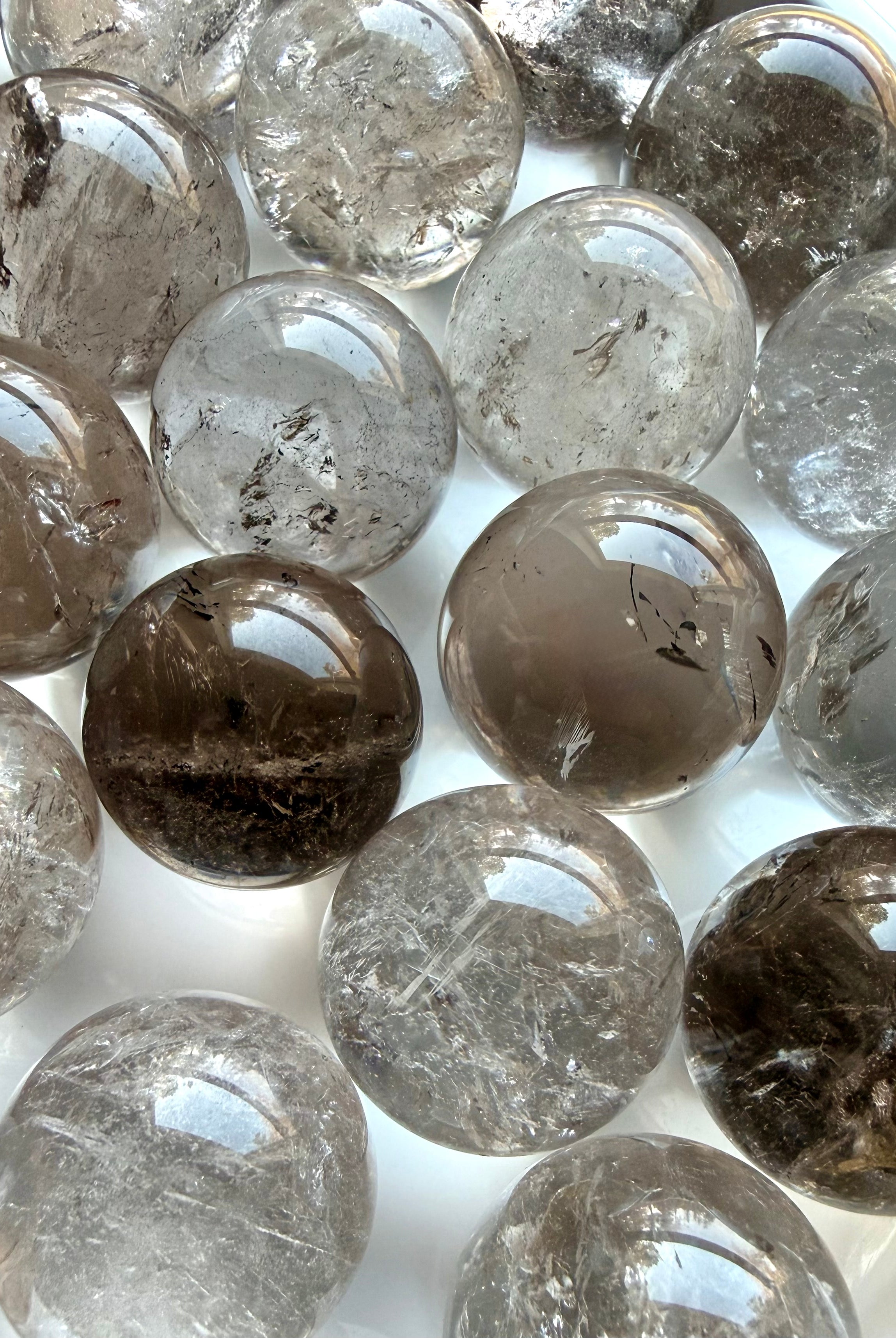 Array of mini Smoky Quartz crystal spheres close up showing color variation and internal patterns
