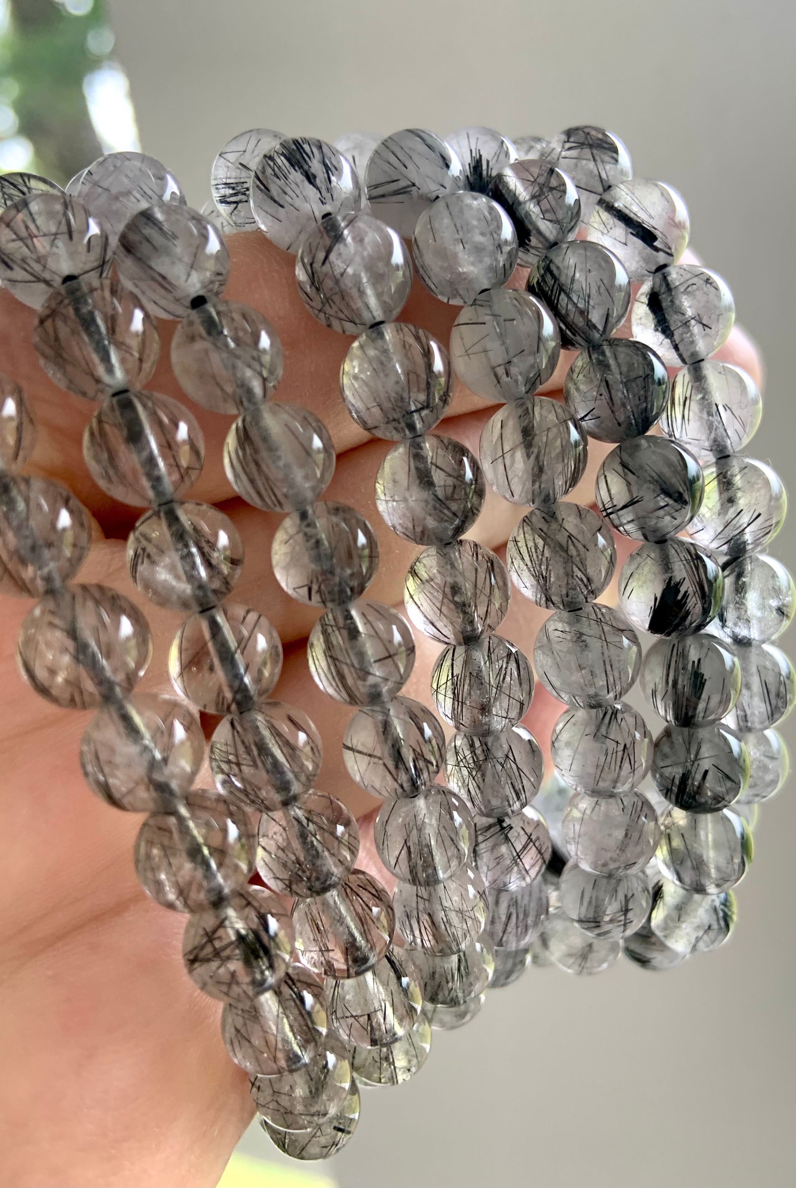 Closeup of Black Tourmaline in Quartz bracelets held to the light, revealing clarity and suspended needle-like inclusions