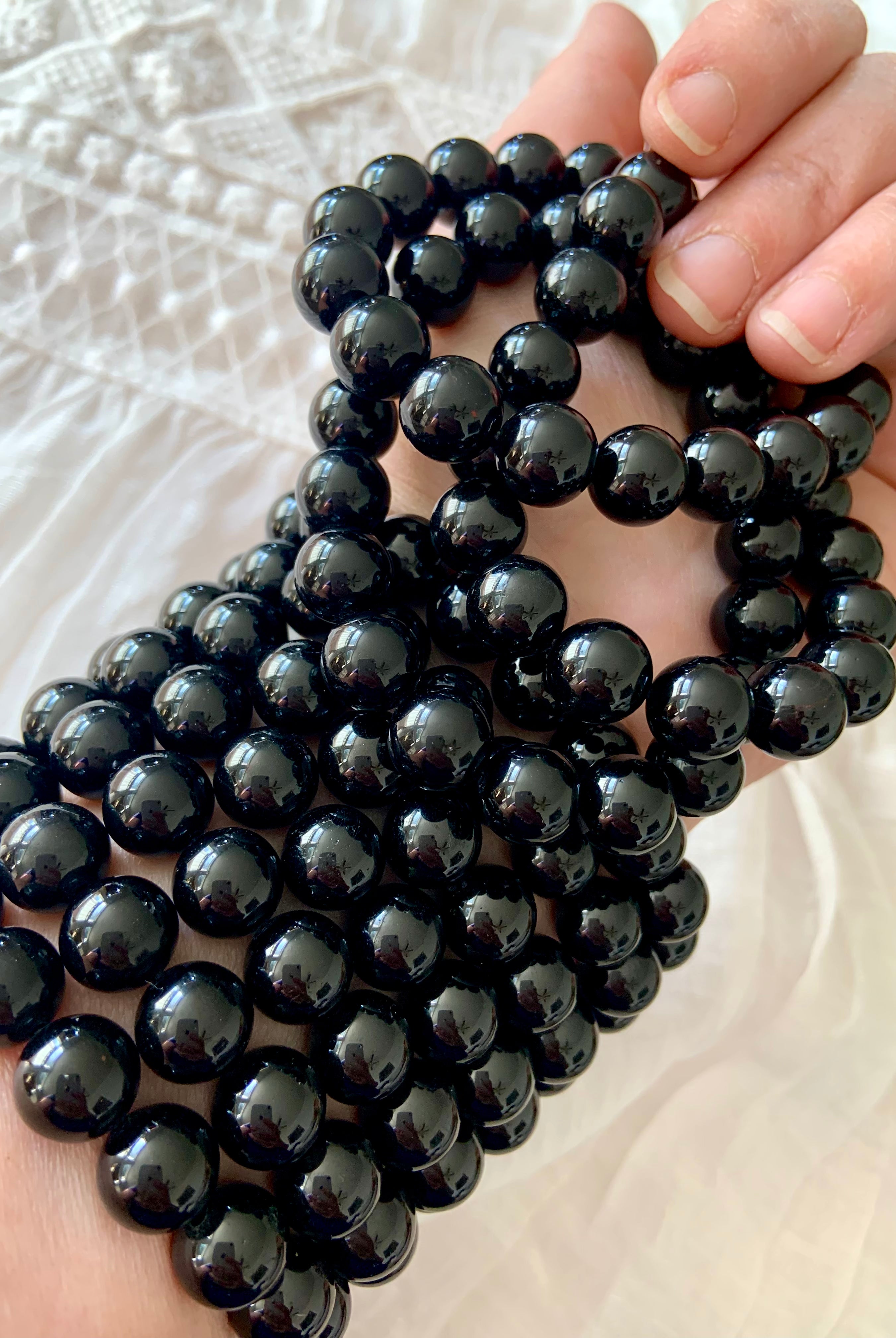 Stack of glossy Black Tourmaline bracelets worn on wrist — high quality crystal beads for grounding and energetic protection