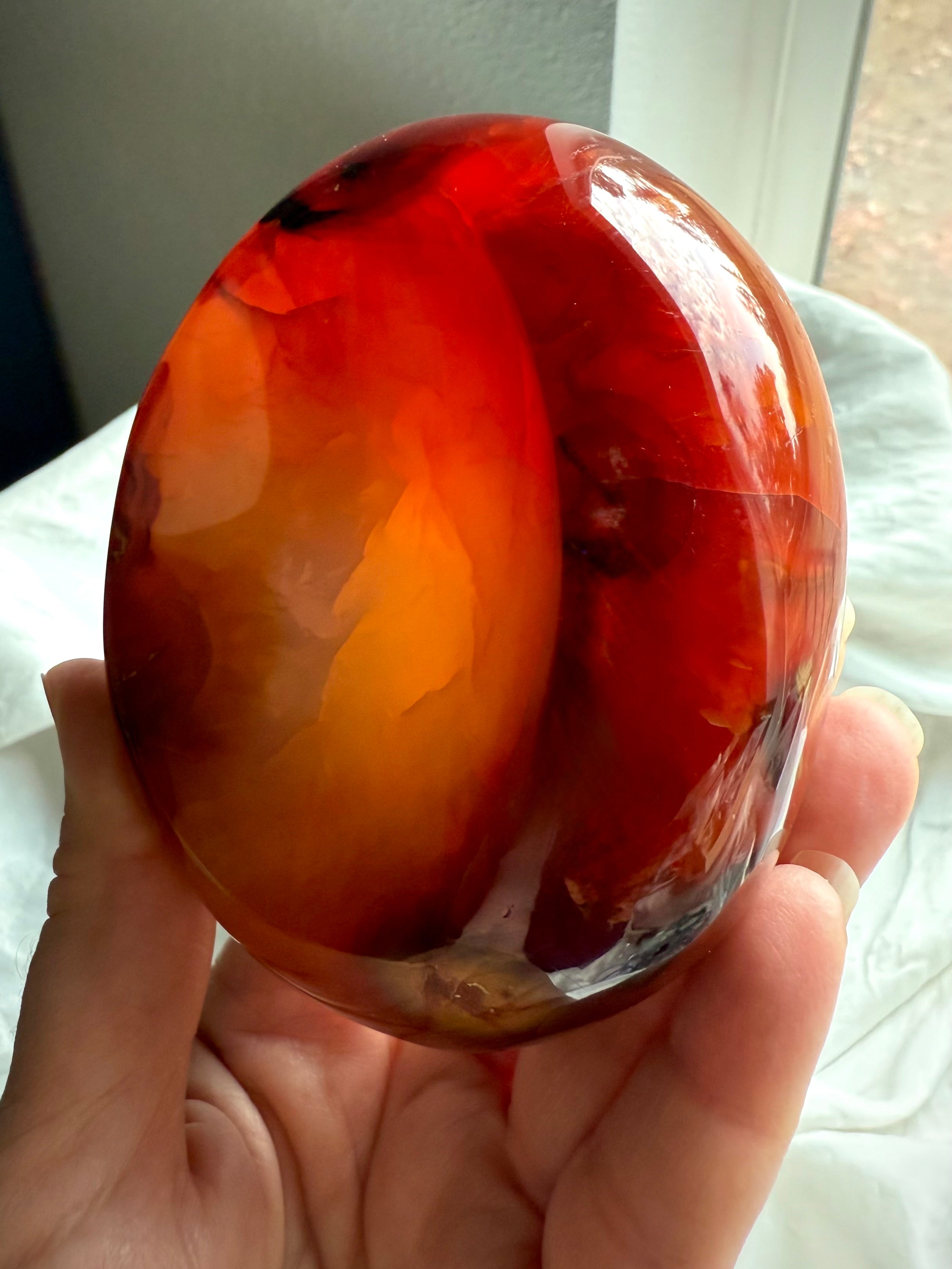 Hand-held Carnelian crystal bowl showing deep red fire tones – healing stone for vitality, passion, and grounding
