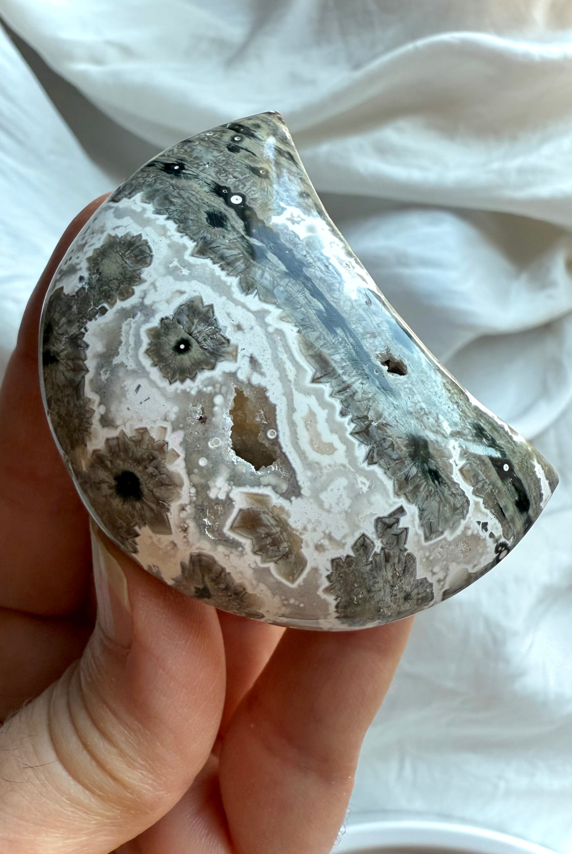 Orbicular Ocean Jasper Crescent Moon with gray, white and charcoal starburst formations, grounding palm stone for strength and inner healing