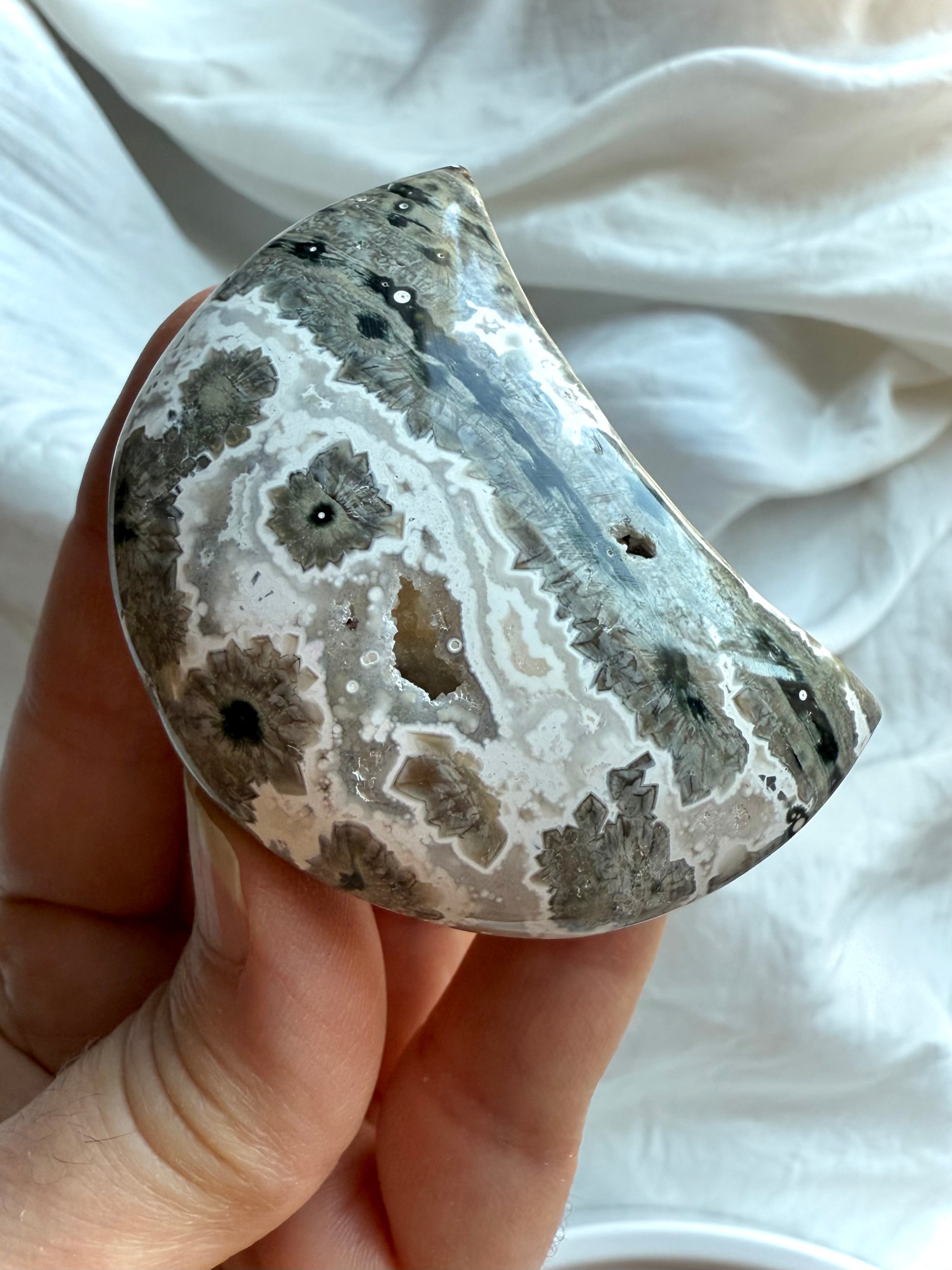 Orbicular Ocean Jasper Crescent Moon with gray, white and charcoal starburst formations, grounding palm stone for strength and inner healing