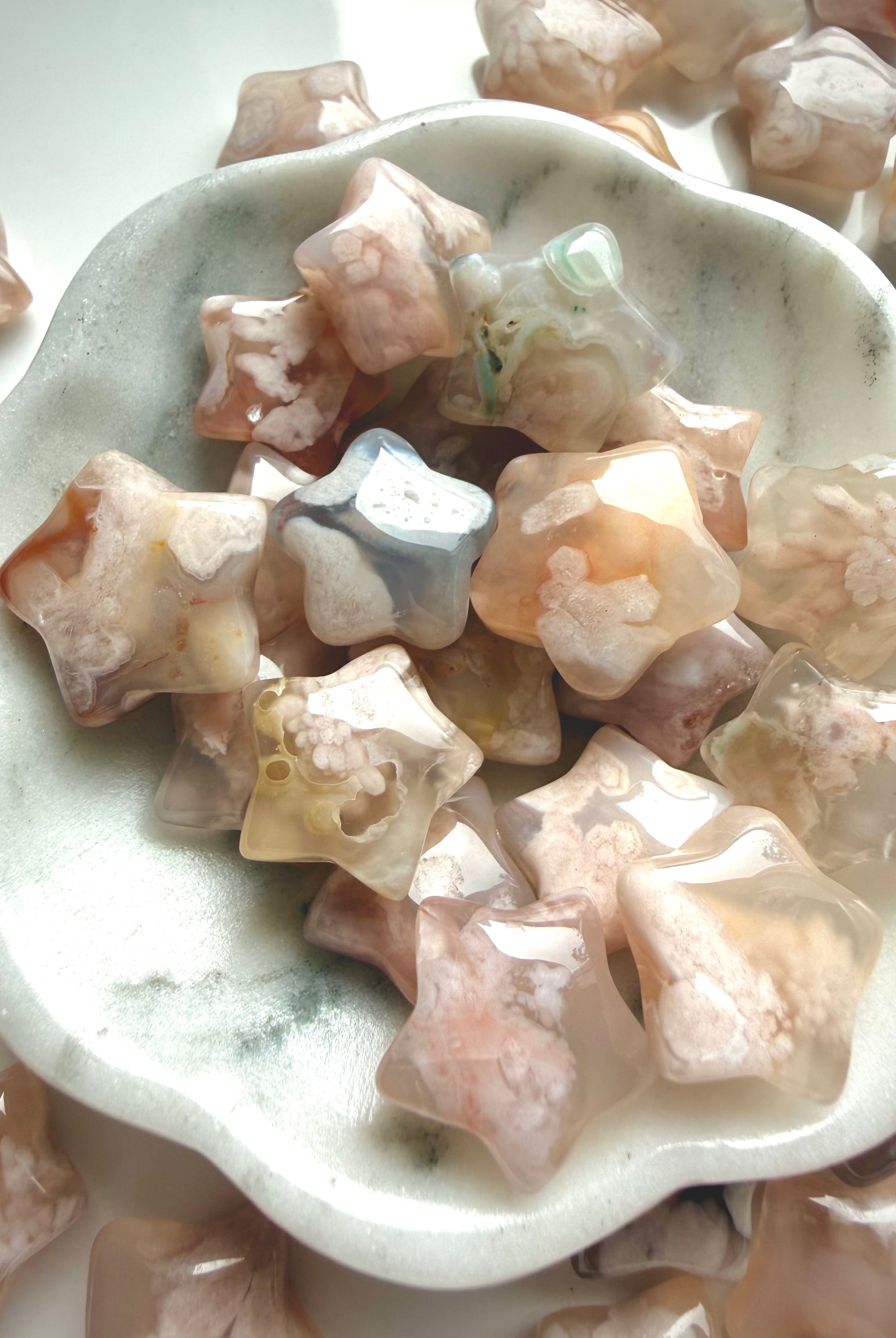 Flower Agate crystal star carvings arranged in a ceramic bowl with soft feminine pastel coloring
