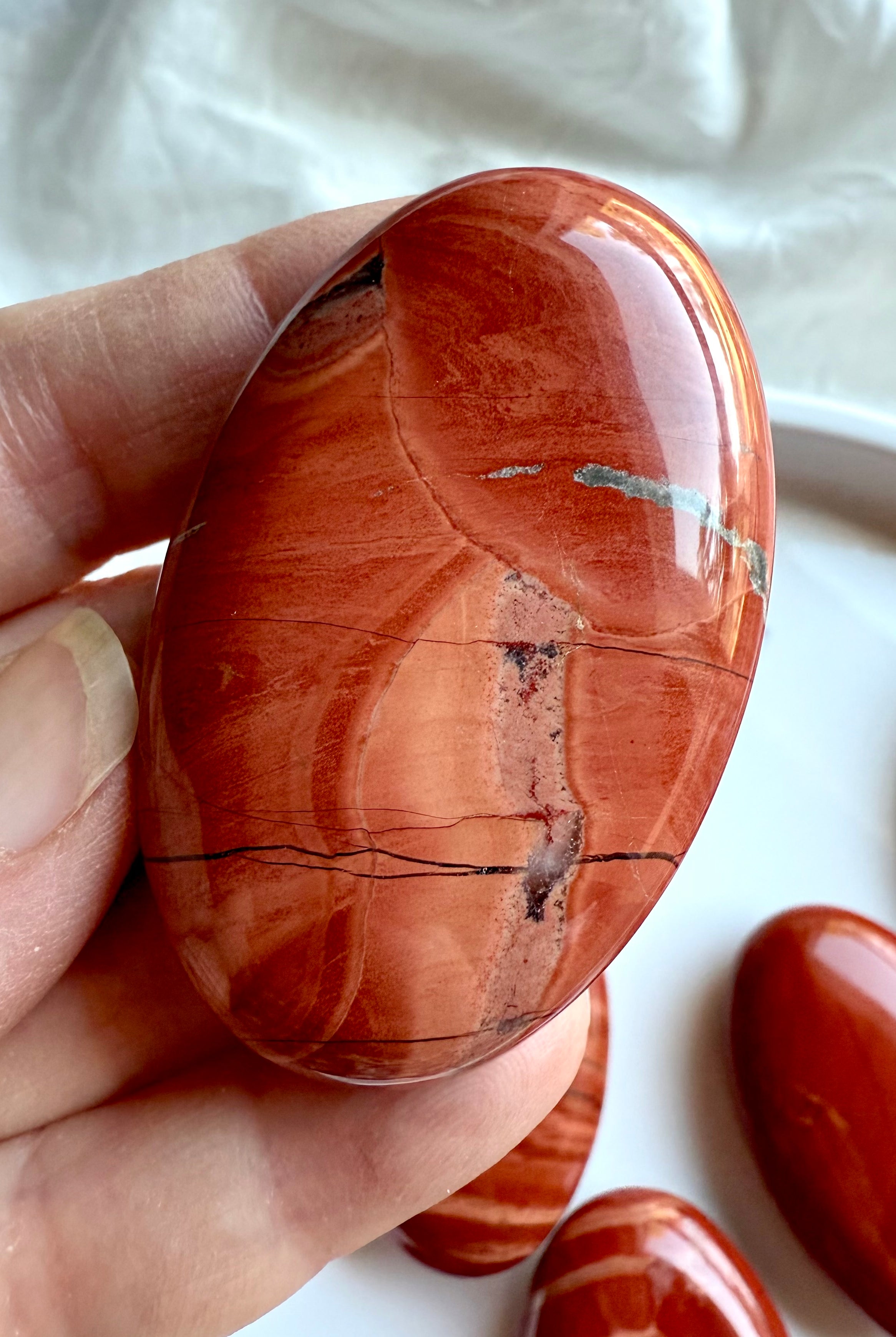 Close-up of Red Jasper palm stone — deep red tones with natural veining and unique mineral patterns.