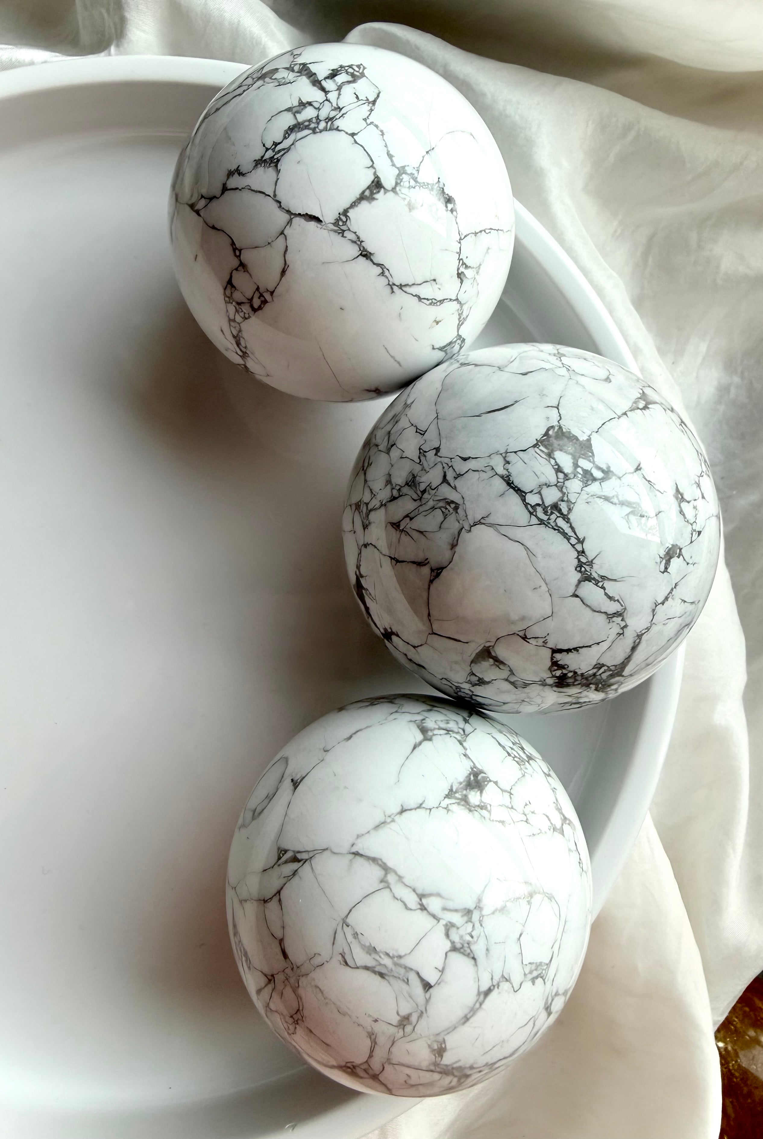 Howlite crystal spheres in white bowl with natural gray veining, polished calming stone spheres for sleep, anxiety relief and peaceful home décor