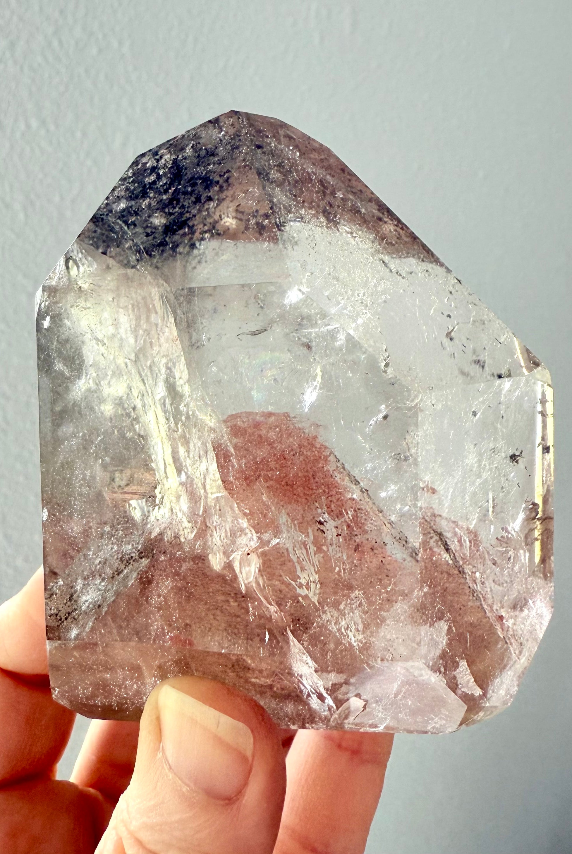 This Lodolite Garden Quartz Tower held to the light to show the big reddish orange phantom pyramid